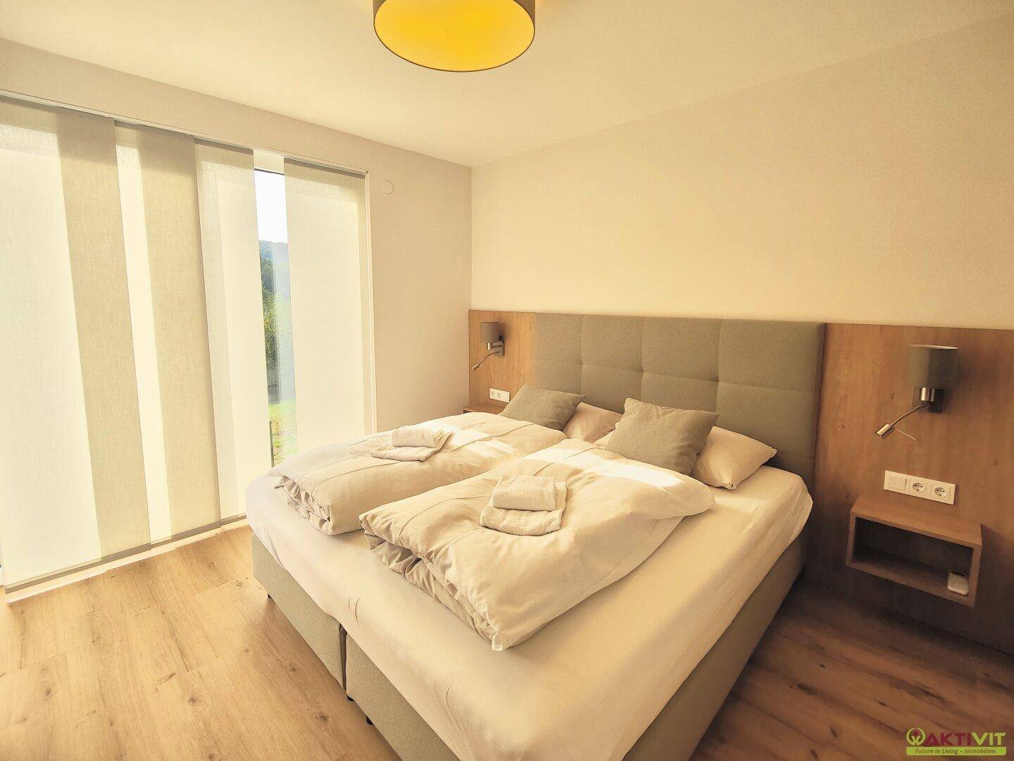 Komfortables Schlafzimmer mit Doppelbett, Holzboden und Zugang zu einem Balkon.