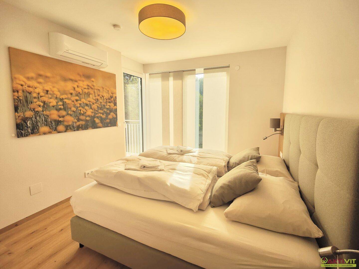 Helles Schlafzimmer mit Doppelbett, Klimaanlage und großem Fenster für viel Tageslicht.