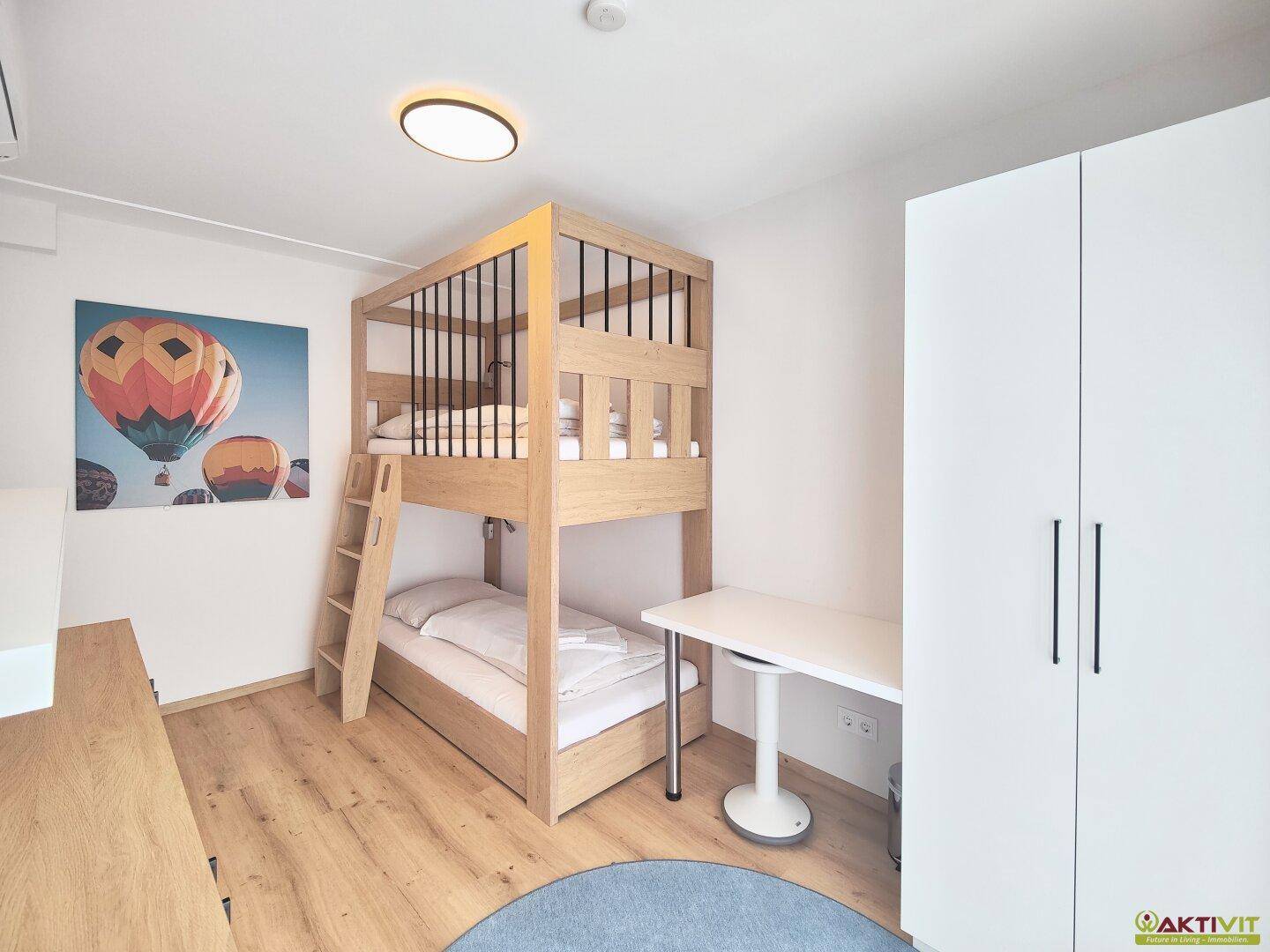 Kinderzimmer mit Etagenbett, Schreibtisch und hellem Holzboden, ideal für Geschwister.