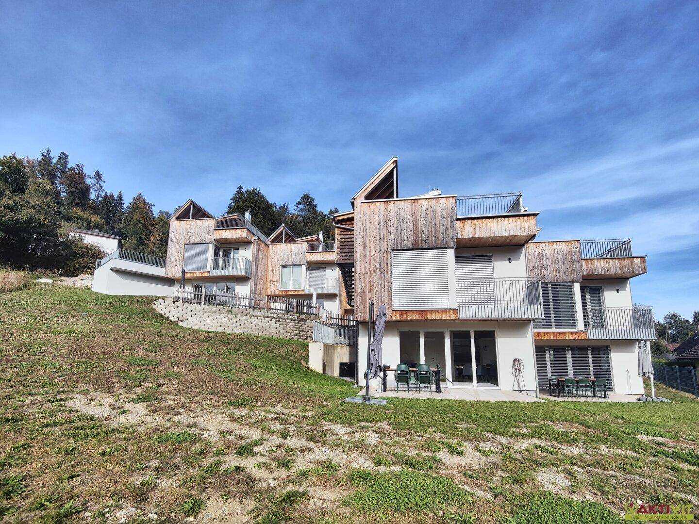 Moderne Architektur mit Holzfassaden und Terrassen, harmonisch in die Natur integriert.