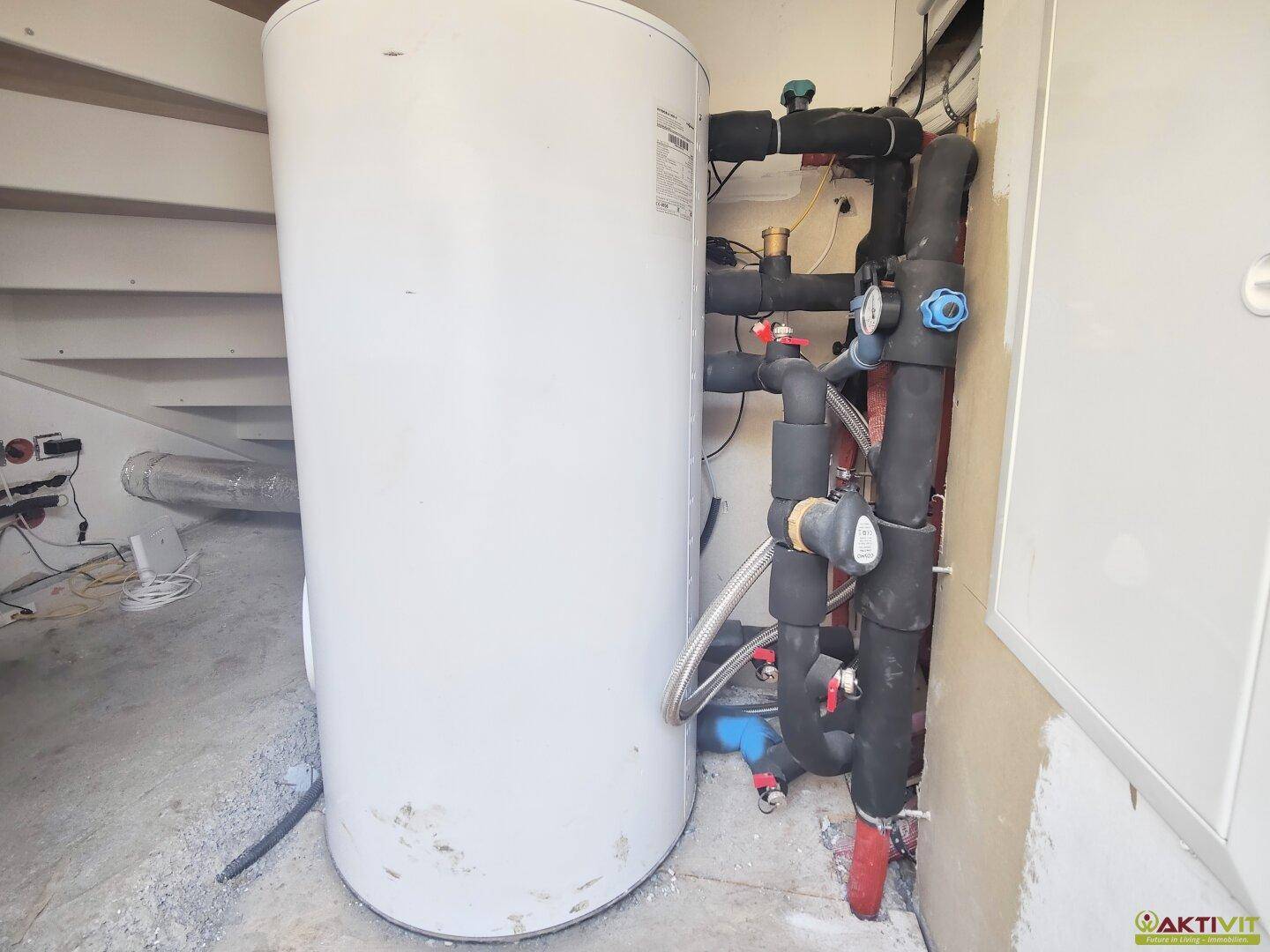 Technikraum mit Warmwasserspeicher und Installationen, wichtig für die Hausversorgung.