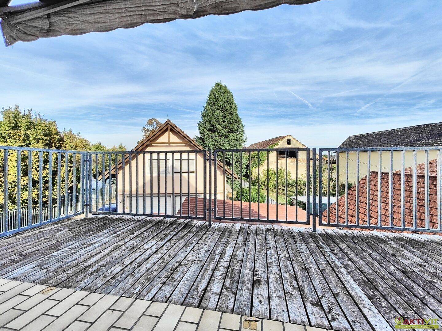 Große Dachterrasse mit Holzboden und Metallgeländer, bietet weite Aussicht auf die Umgebung.