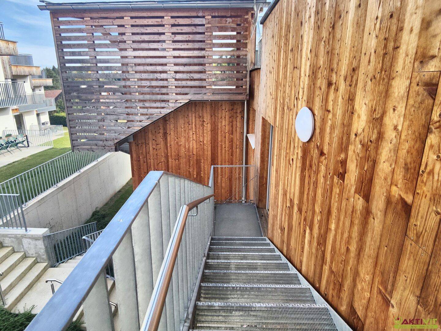 Außentreppe aus Metall führt zu den oberen Etagen der modernen Holzfassade.