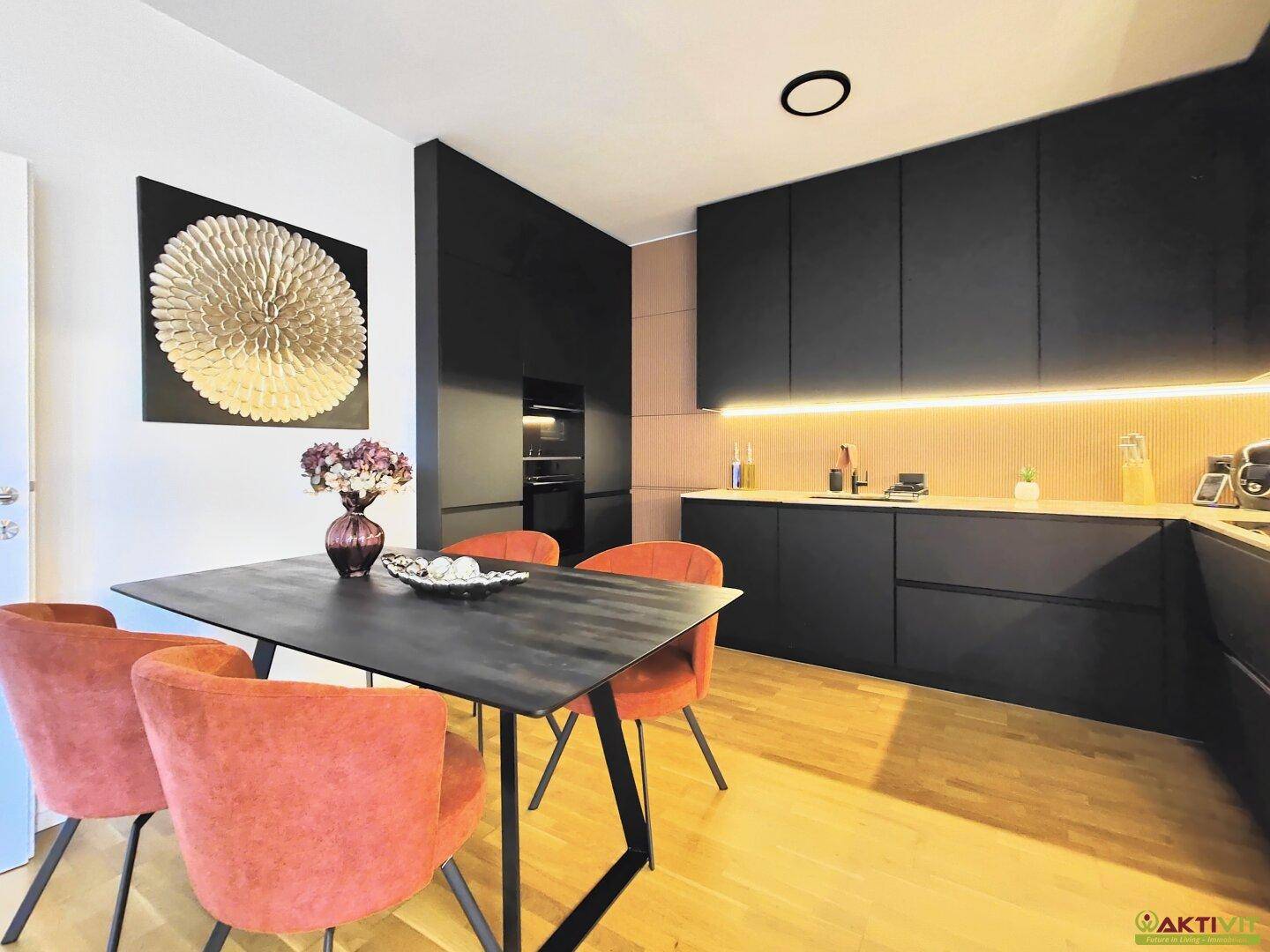 Moderner Essbereich mit orangefarbenen Stühlen und eleganter schwarzer Küche mit Holz-Arbeitsplatte.