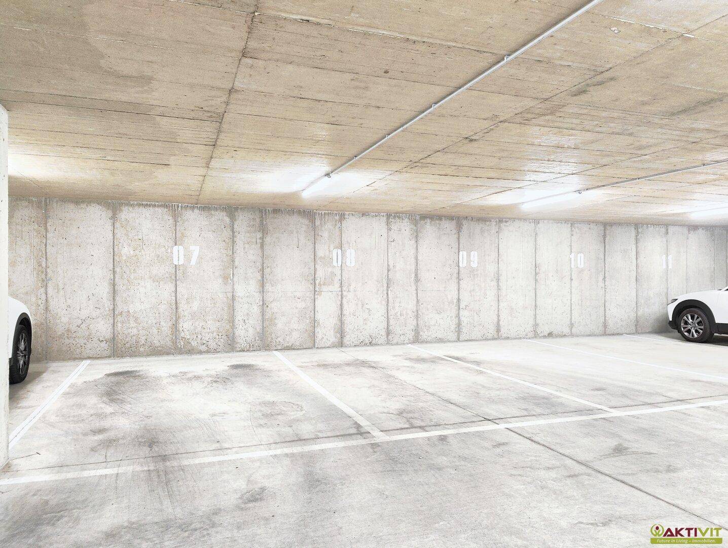 Tiefgarage mit Betonwänden und markierten Stellplätzen für Fahrzeuge.