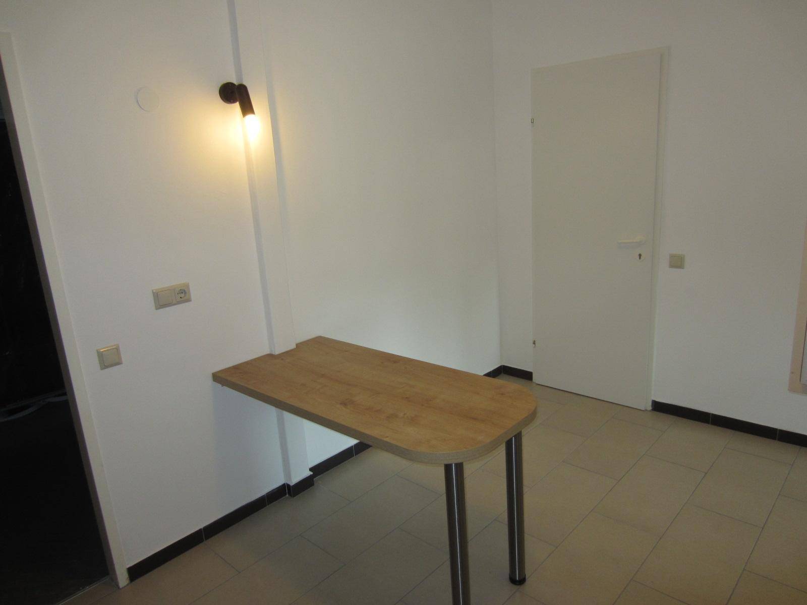 Kleiner Essbereich mit Wandtisch und Fliesenboden in hellem Raum.