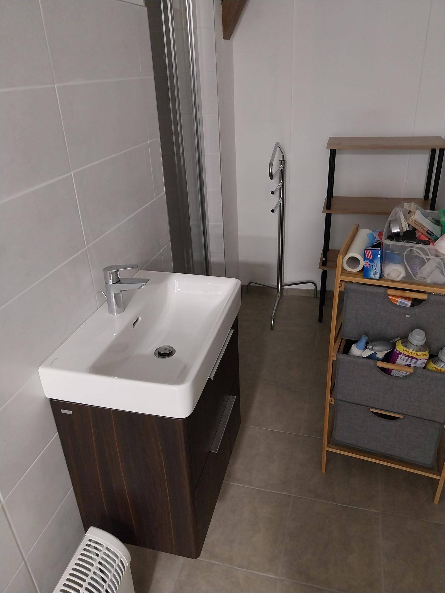 Badezimmer mit modernem Waschtischunterschrank, rechteckigem Waschbecken und hellen Fliesen.