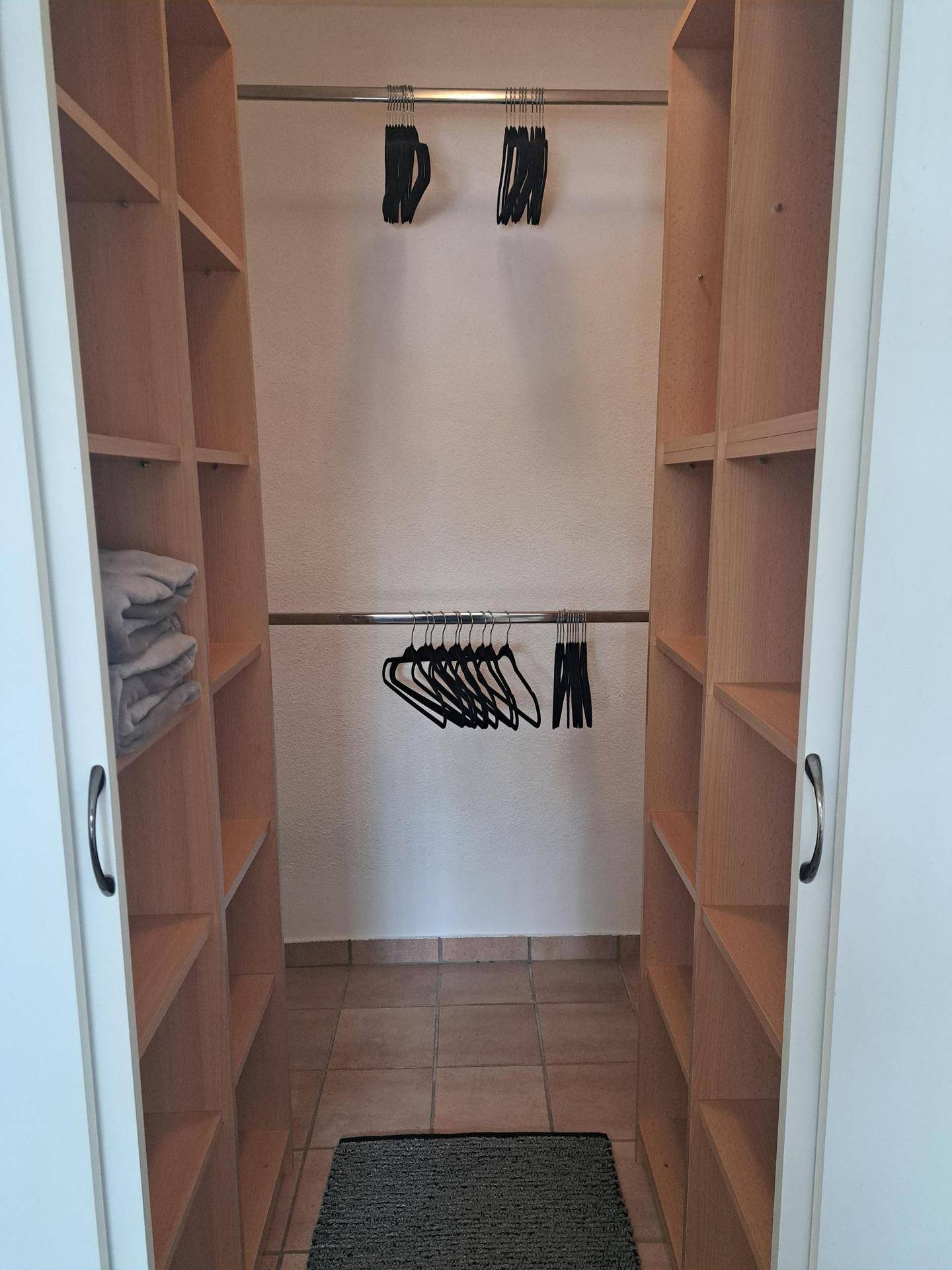Praktischer begehbarer Kleiderschrank mit Regalen und Kleiderstangen für viel Stauraum.