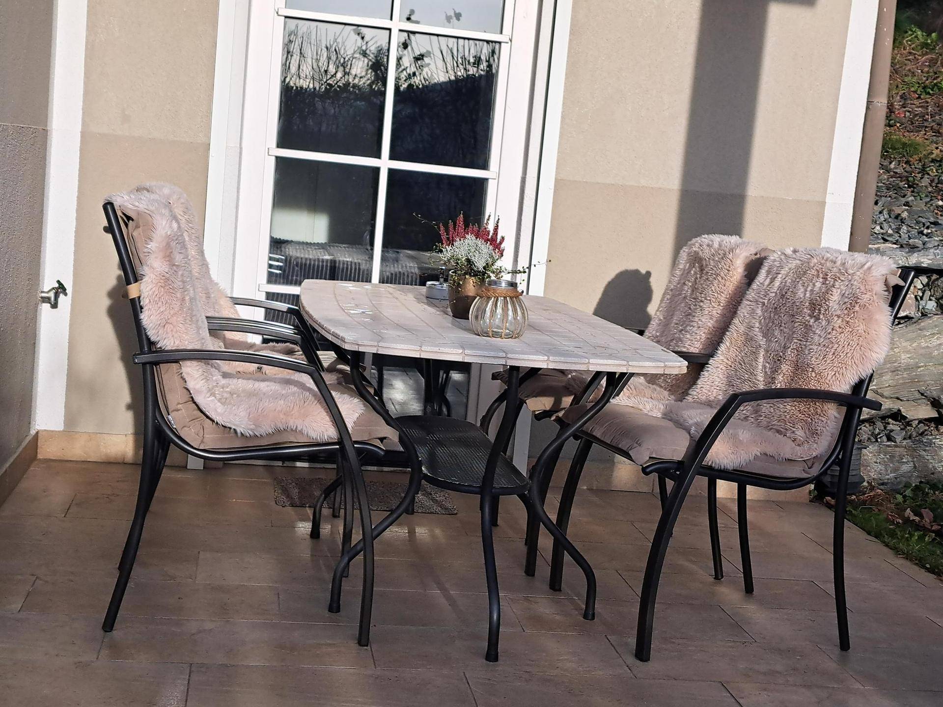 Kleine, gemütliche Terrasse mit Tisch und Stühlen, ideal für entspannte Stunden im Freien.