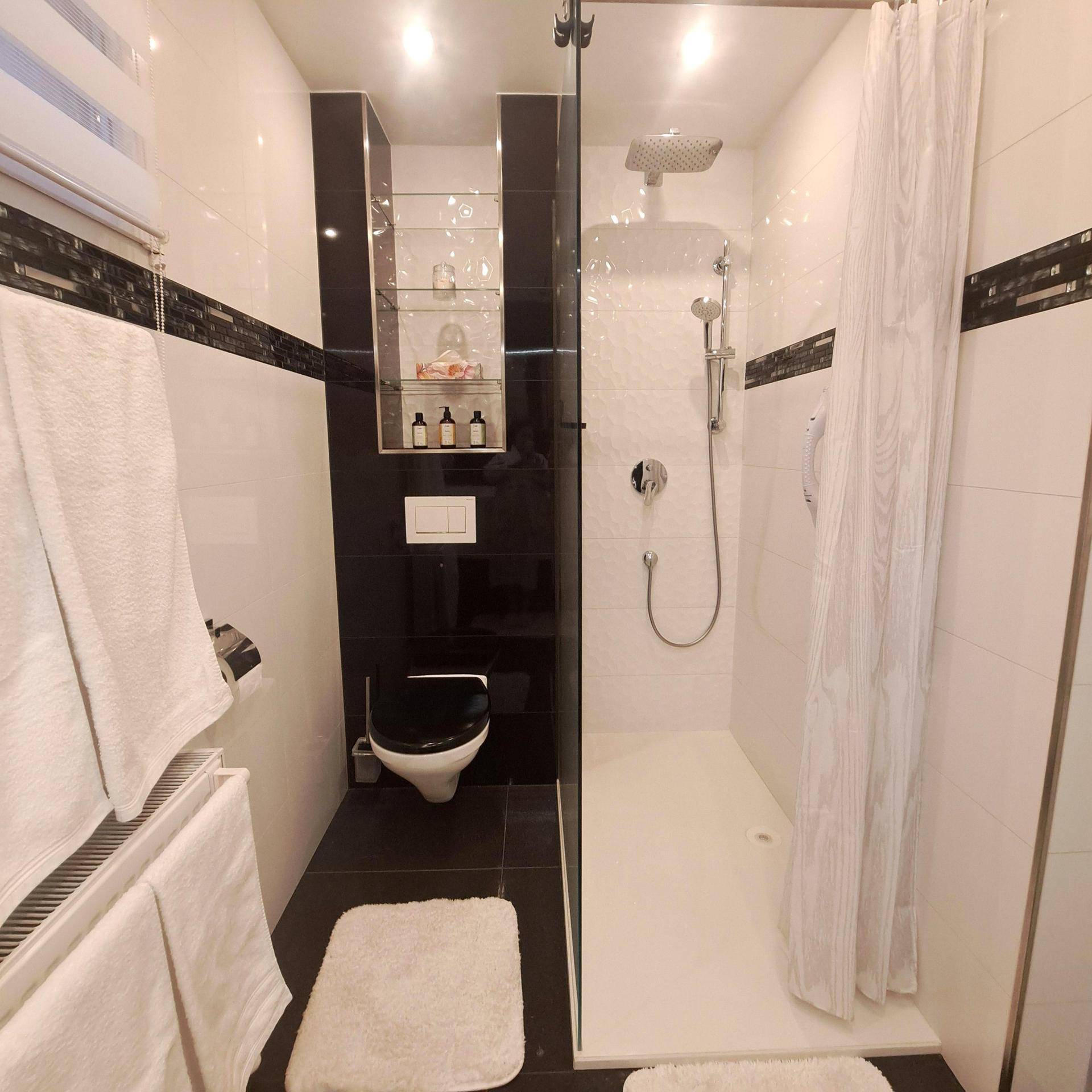 Modernes Badezimmer mit ebenerdiger Dusche und wandhängendem WC, in Schwarz-Weiß gehalten.