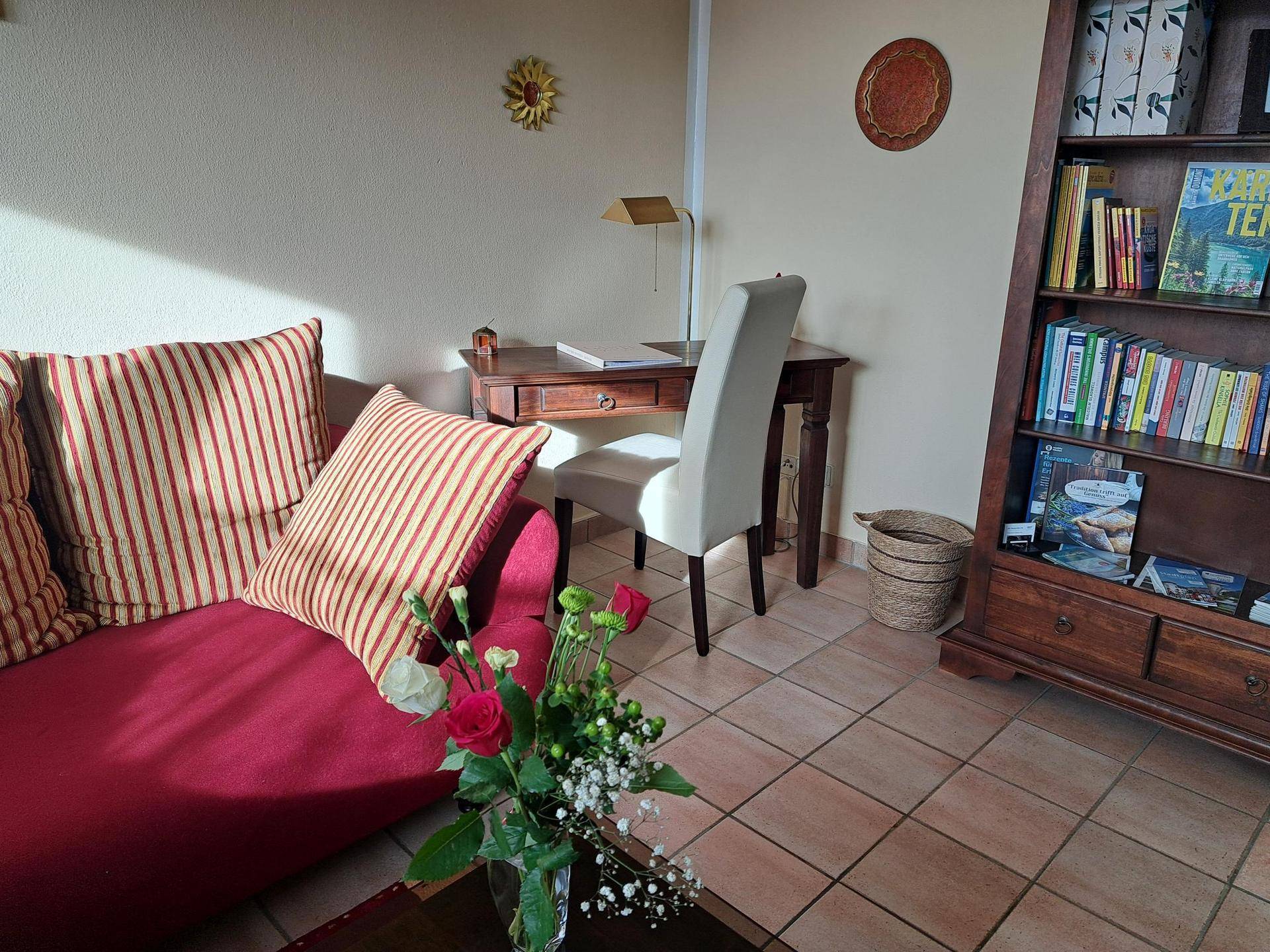 Wohnbereich mit Schreibtisch, Bücherregal und bequemer Sitzgelegenheit, ideal zum Arbeiten und Entspannen.