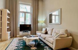 Gemütliches Wohnzimmer mit beigem Sofa, großem Fenster und gemustertem Teppichboden.