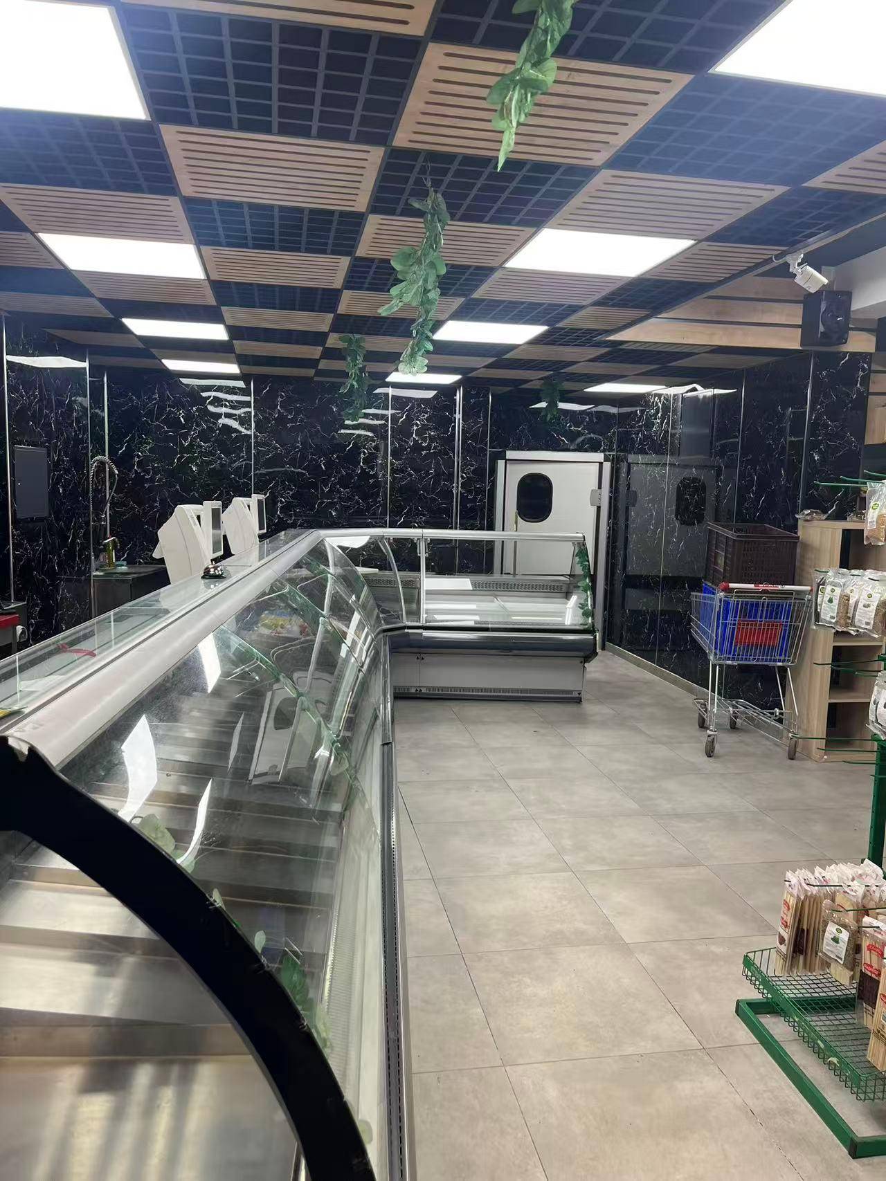 Innenansicht eines modernen Ladengeschäfts mit Kühltheken, dunklen Marmorwänden und Deckenbeleuchtung.