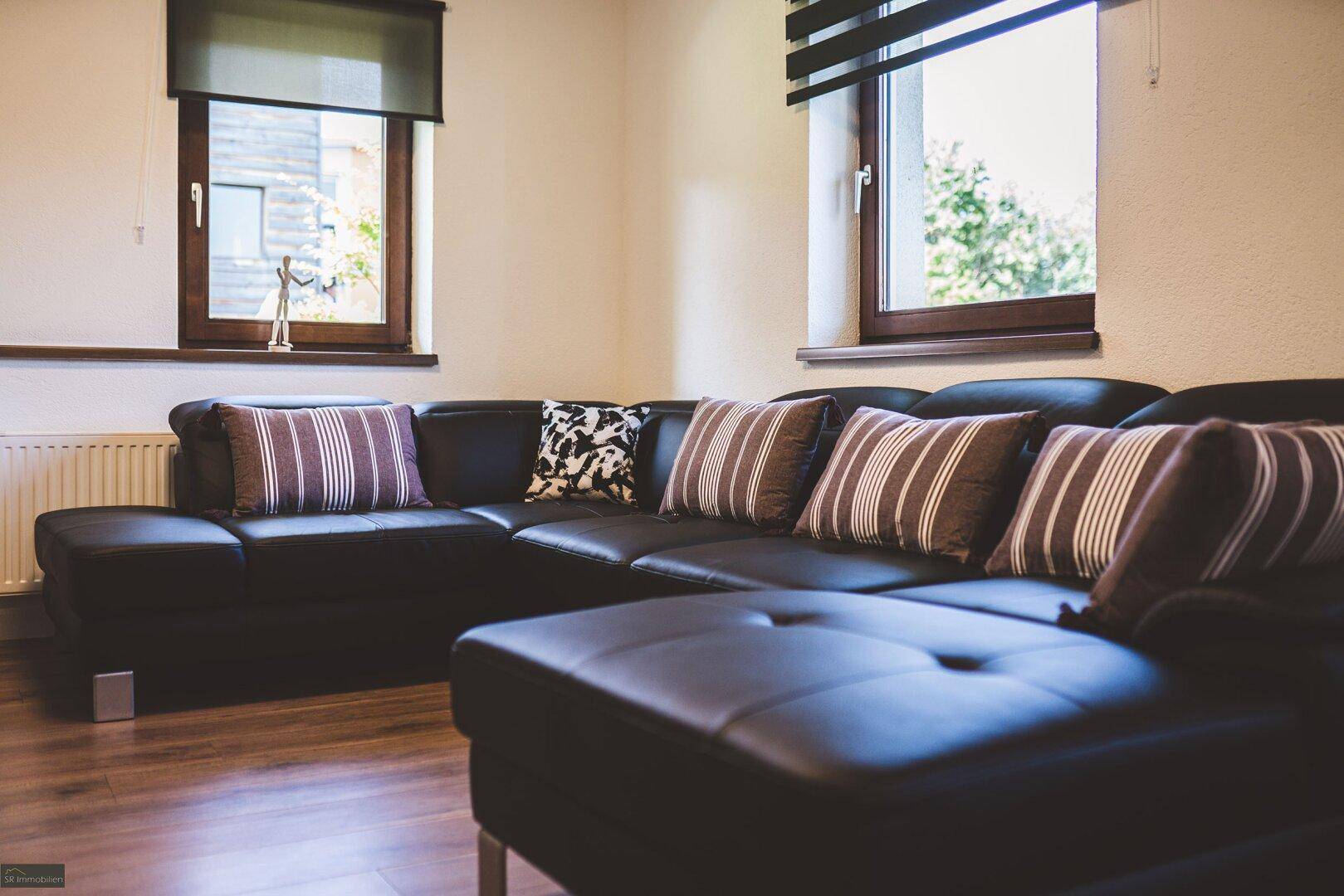 Gemütliches Wohnzimmer mit großem Ecksofa und Holzboden, perfekt zum Entspannen.