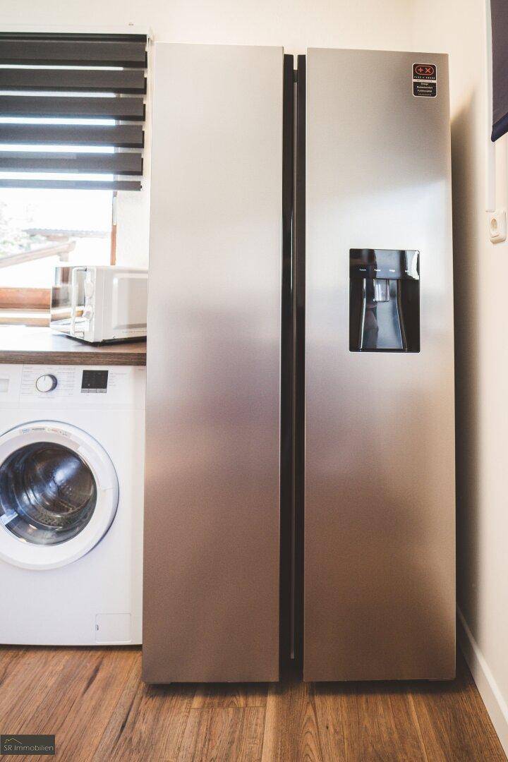 Großer amerikanischer Kühlschrank und Waschmaschine in der Küche, praktisch und modern.