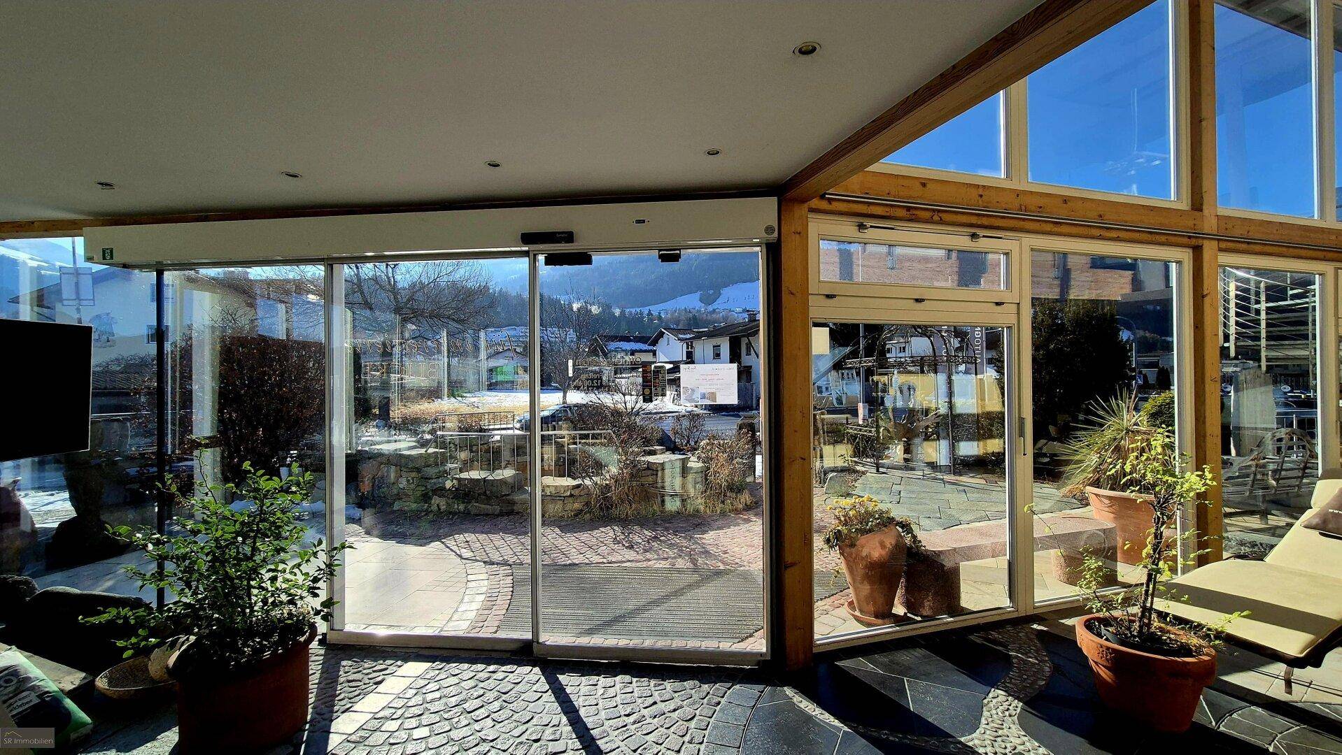 Weitläufiger Innenraum mit automatischer Glasschiebetür und Panoramablick auf die verschneite Umgebung und Berge.