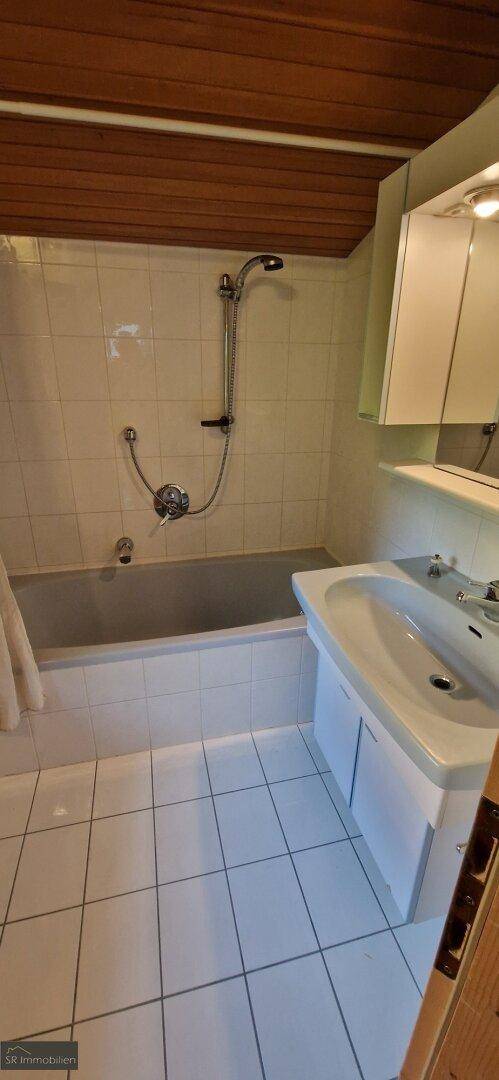 Funktionales Badezimmer mit Badewanne, Duschvorrichtung, Waschbecken und Spiegelschrank.