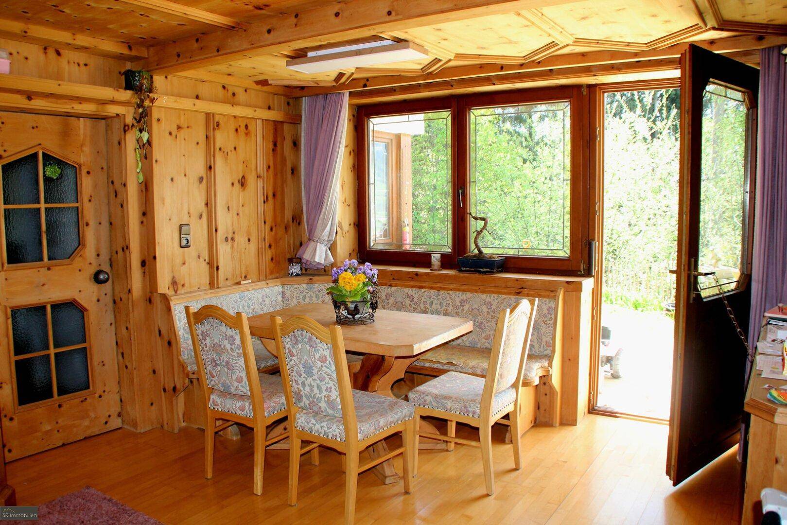 Gemütlicher Essbereich im alpinen Stil mit Holztäfelung, Eckbank und Zugang zum Garten.