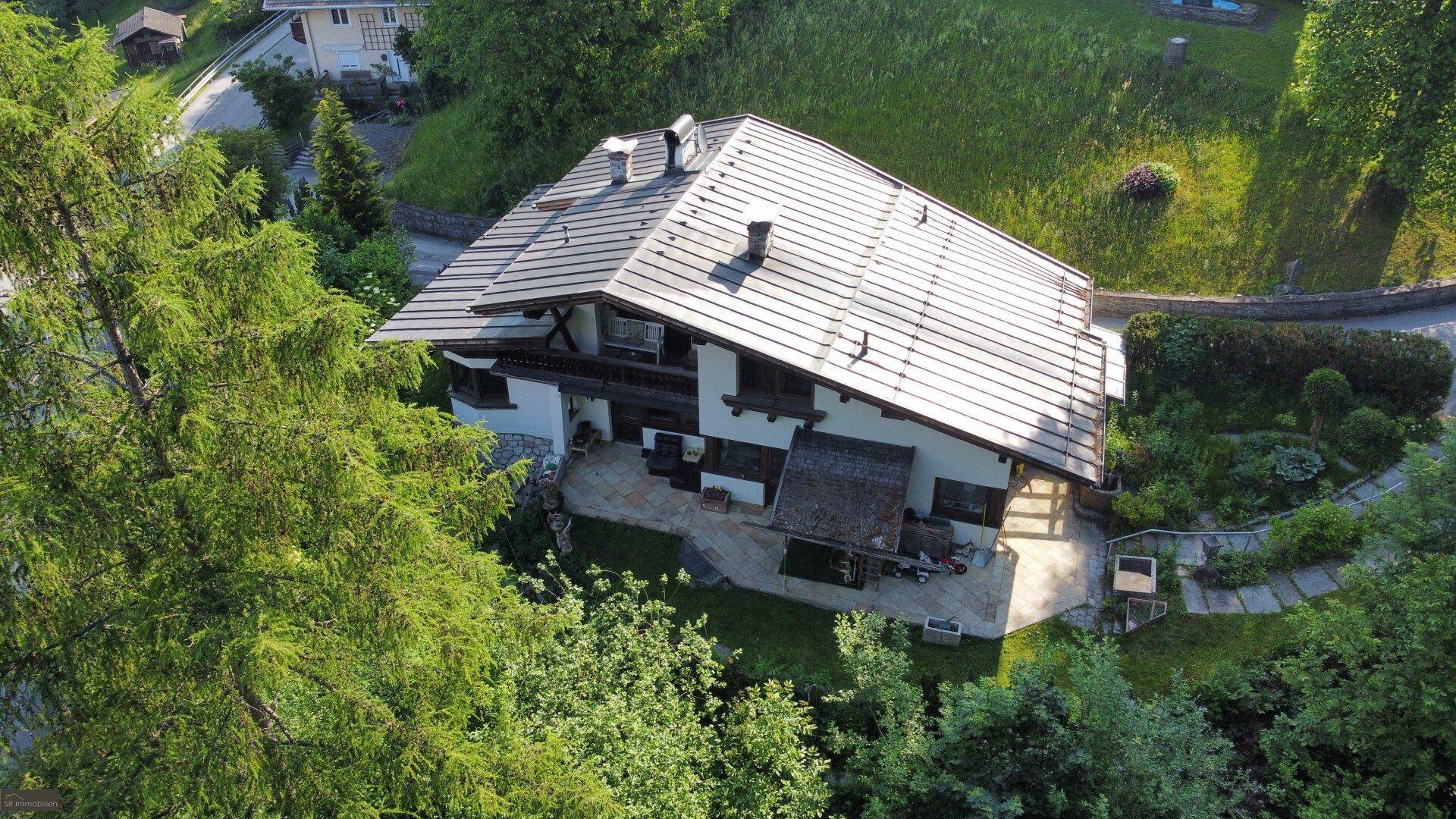 Charmantes Wohnhaus im alpinen Stil mit großem Satteldach, gepflegtem Garten und einer Terrasse.