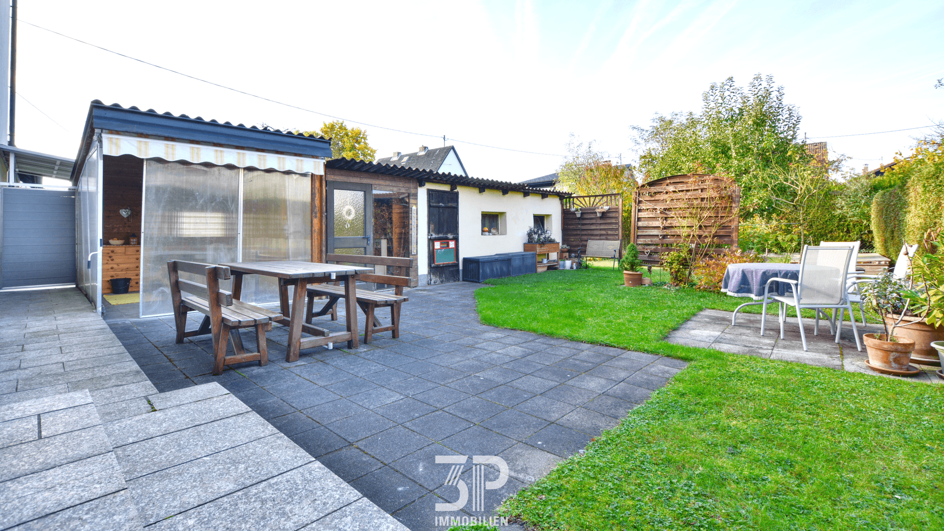 Gepflasterte Terrasse mit Sitzgelegenheiten und angrenzendem Rasenbereich.