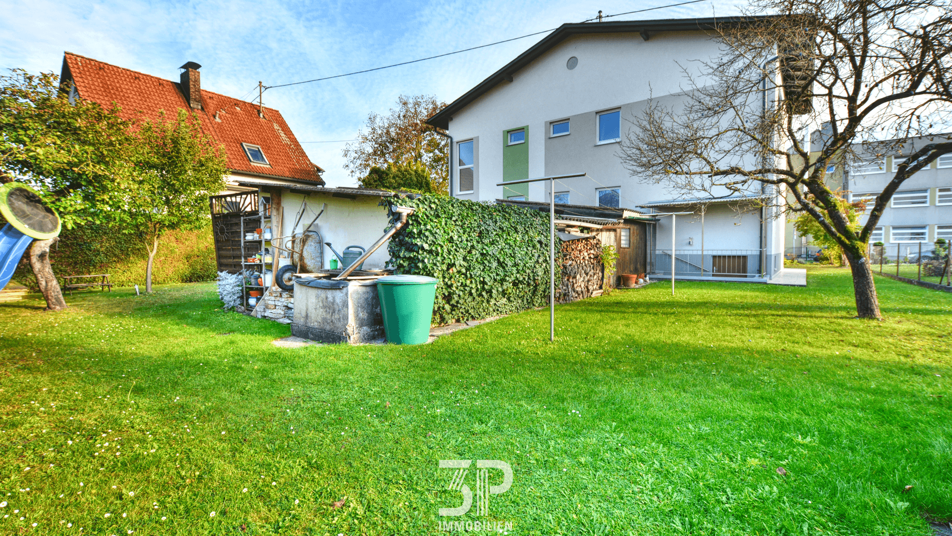 Großer, gepflegter Garten mit Rasenfläche, Bäumen und Spielgeräten.