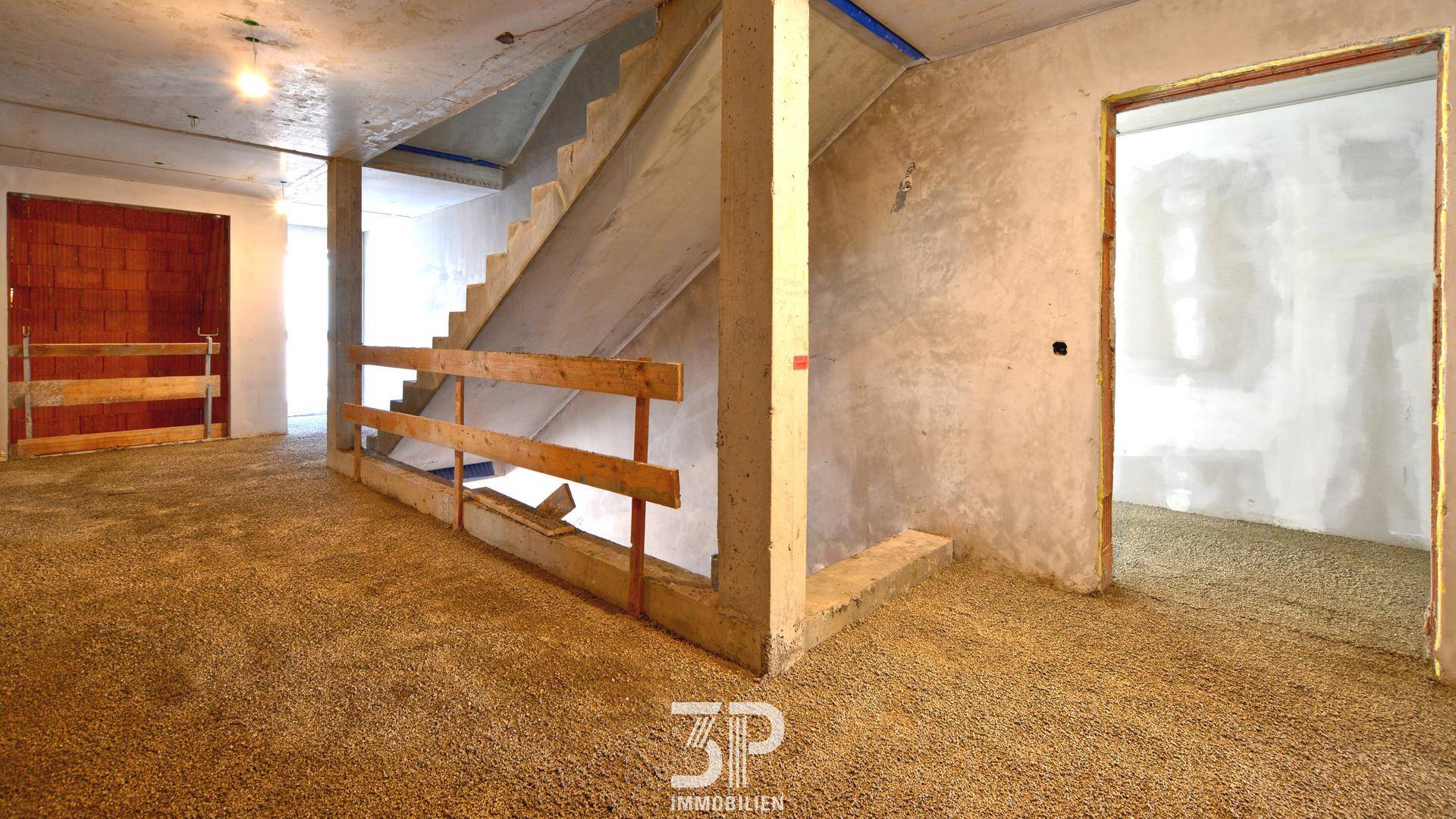 Innenbereich im Rohbau mit Treppenaufgang und sichtbaren Bauelementen, bereit für den Ausbau.