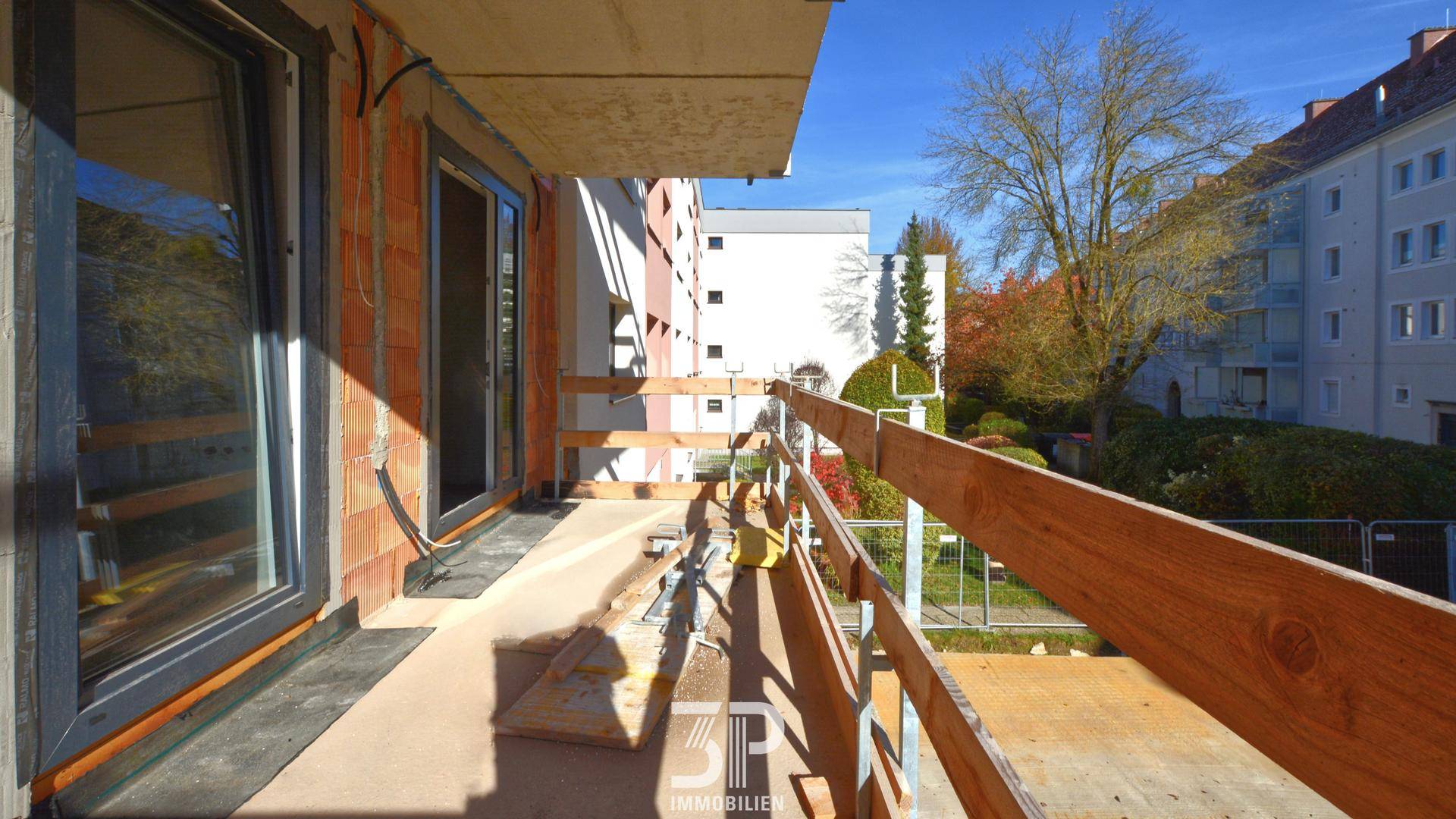 Balkon im Rohbau mit provisorischem Geländer und Blick auf die Umgebung.