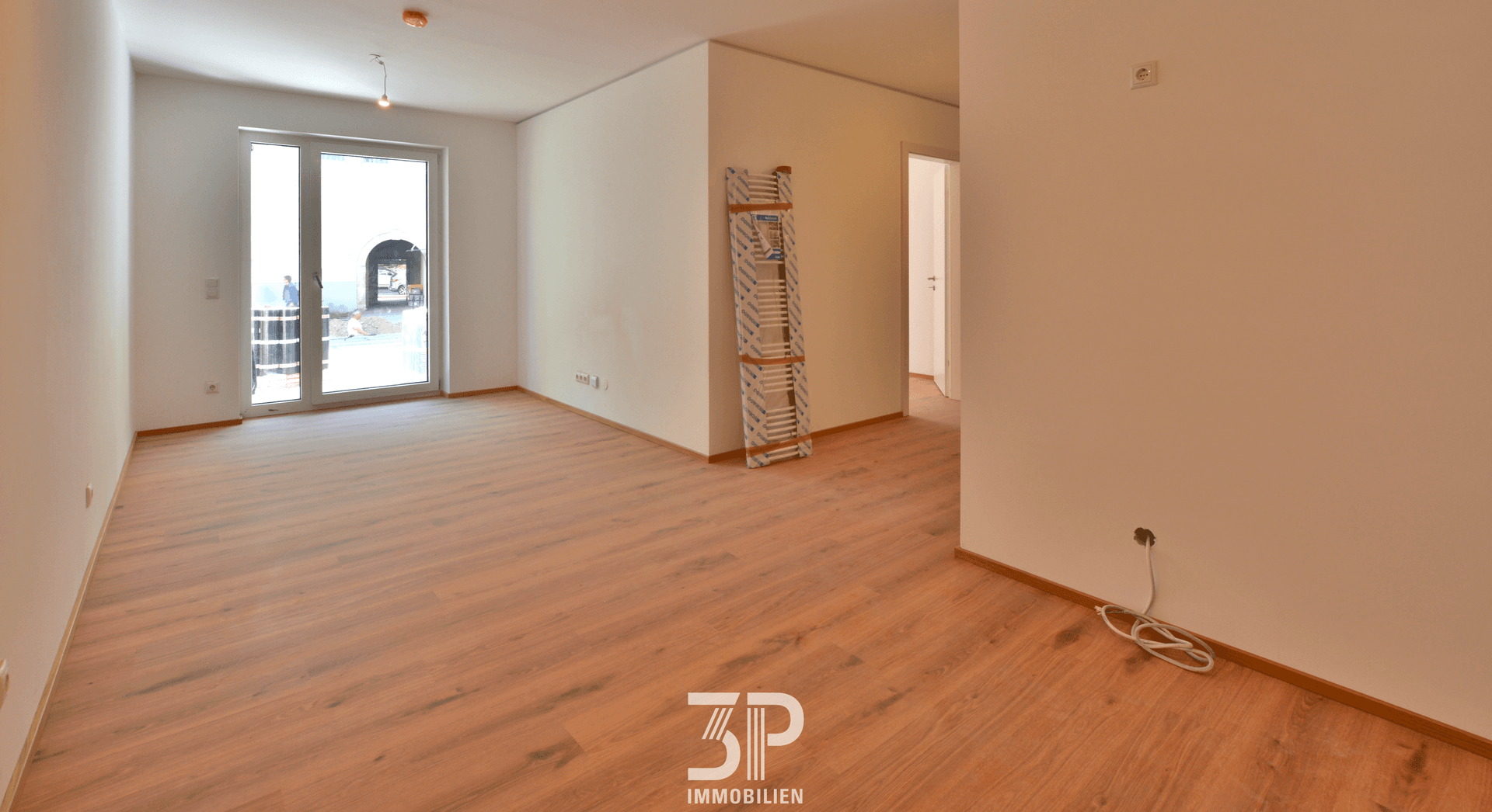Heller Wohnraum mit Laminatboden und großem Fenster, bereit für individuelle Gestaltung.