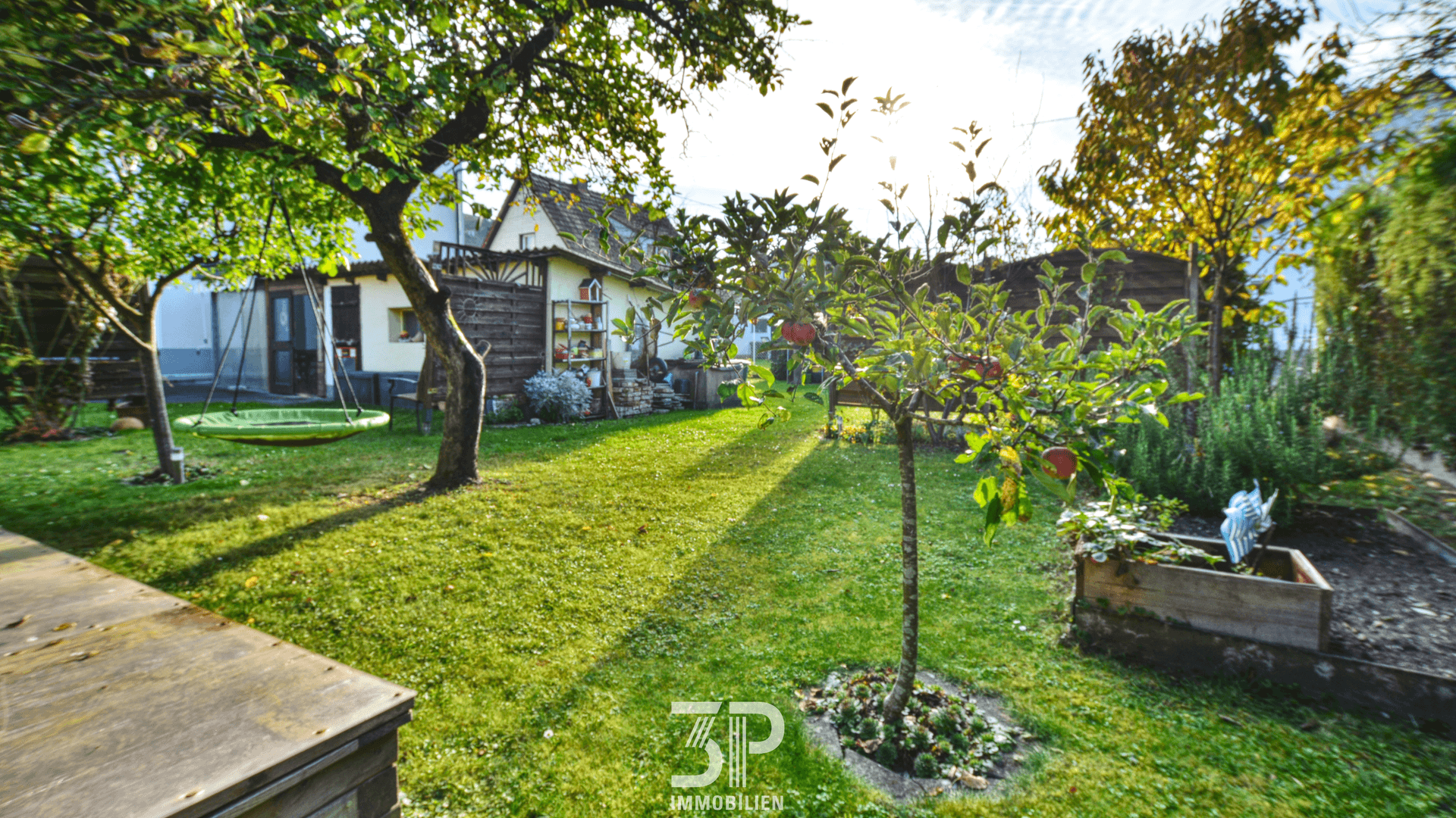 Sonniger Garten mit Obstbäumen, Rasen und viel Grün.