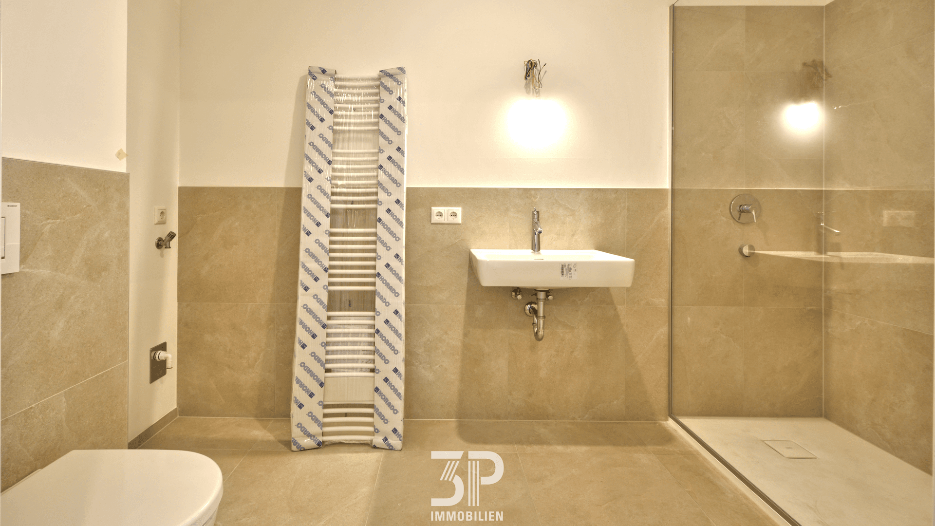 Modernes Badezimmer mit beigefarbenen Fliesen, ebenerdiger Dusche und Handtuchheizkörper.