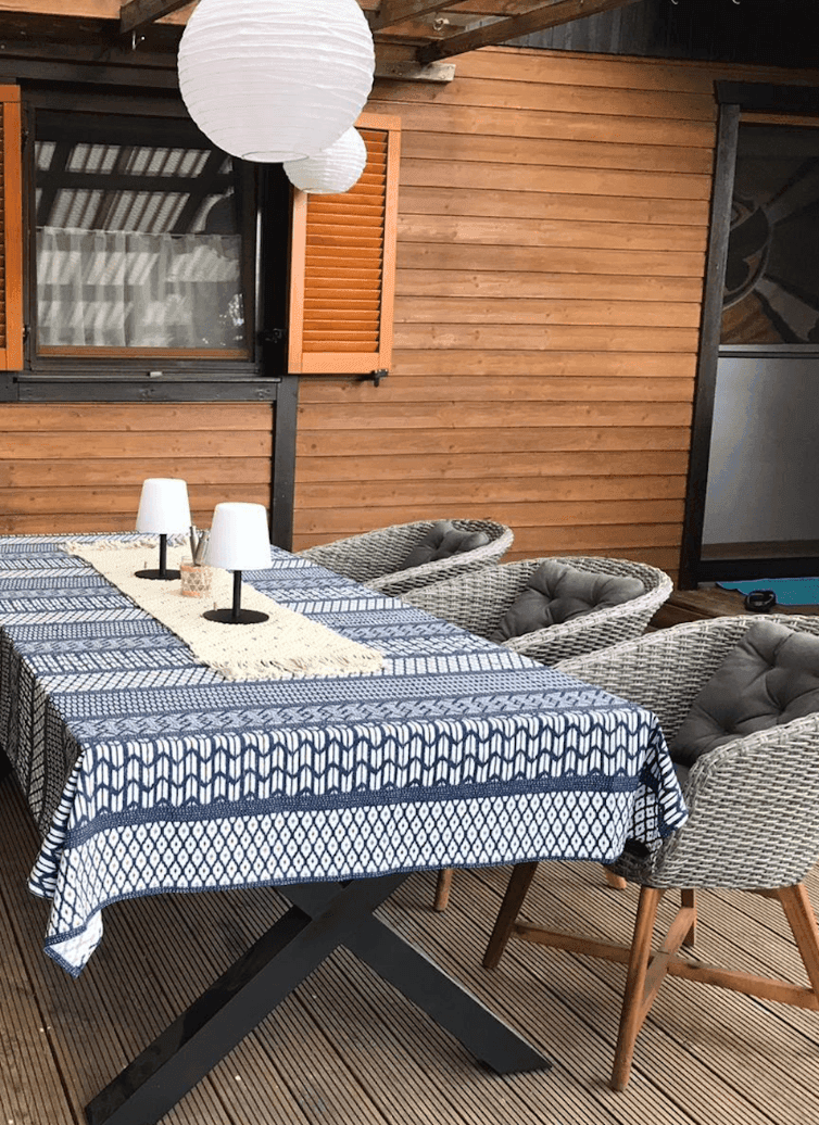 Detailansicht des Esstisches auf der Holzterrasse mit dekorativer Tischdecke und Laternen.