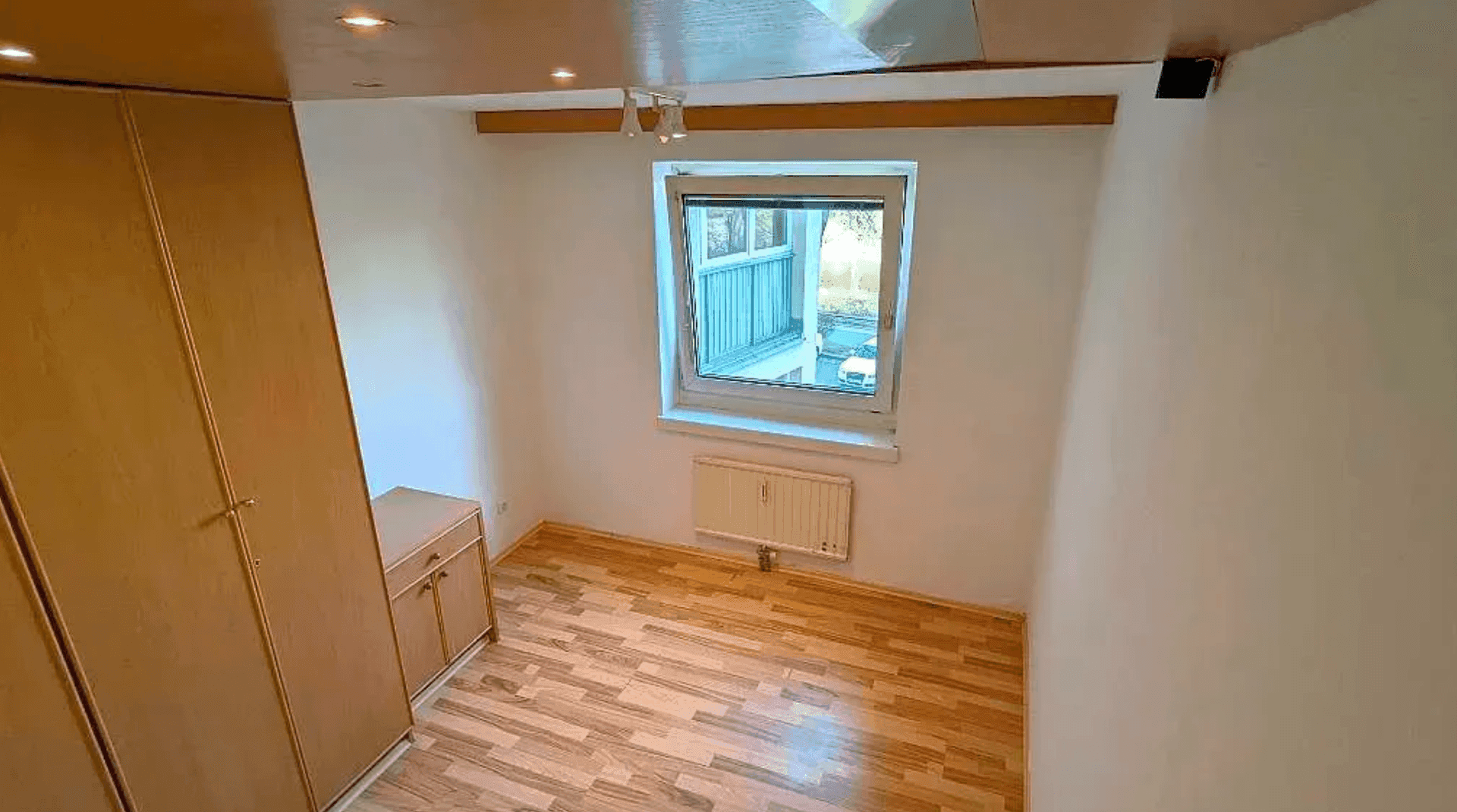 Leeres Zimmer mit Holzboden und Fenster, bereit zur individuellen Gestaltung.