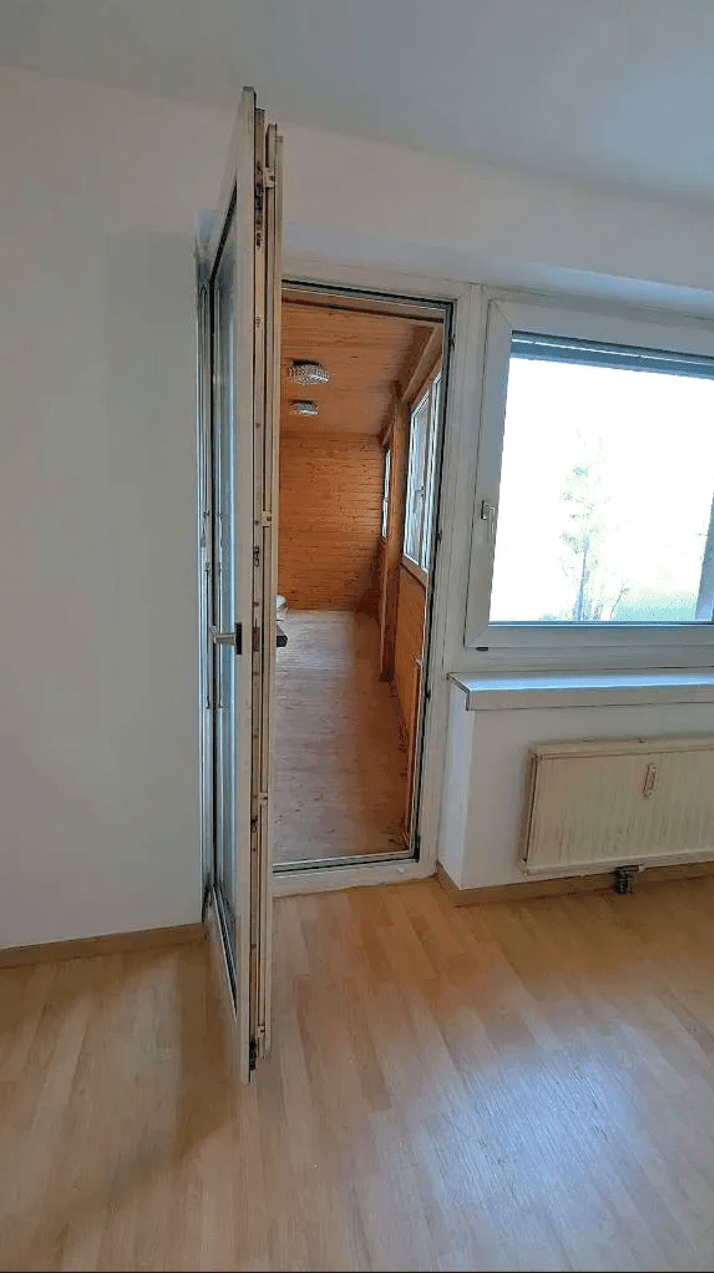 Helle, verglaste Loggia mit Holzverkleidung, bietet einen geschützten Außenbereich.