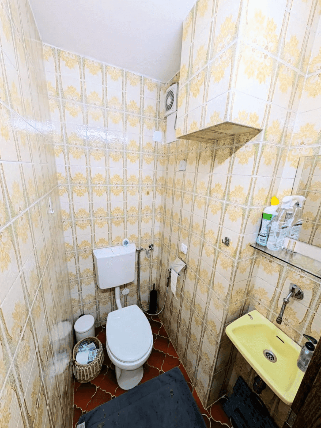 Kleines Gäste-WC mit Toilette und Waschbecken, dekoriert mit gemusterten Fliesen.