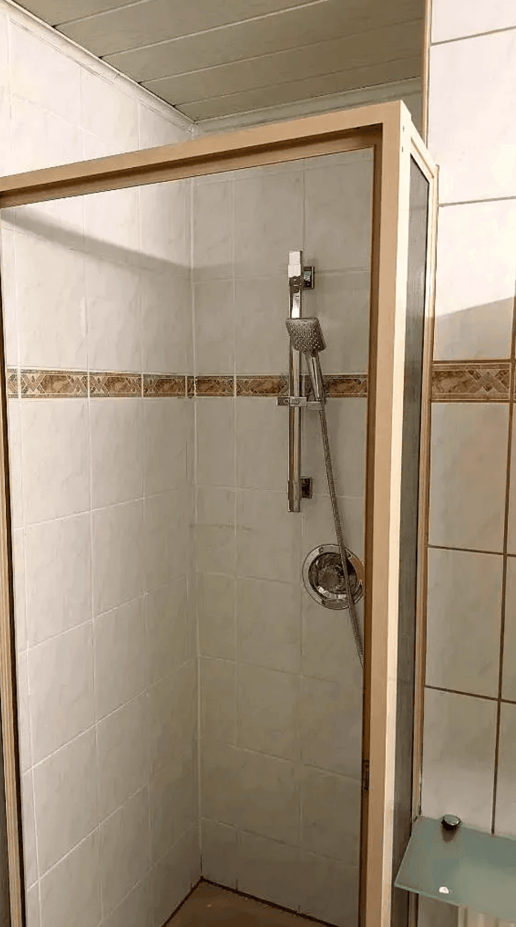 Duschkabine im Badezimmer mit Fliesen und moderner Duscharmatur.