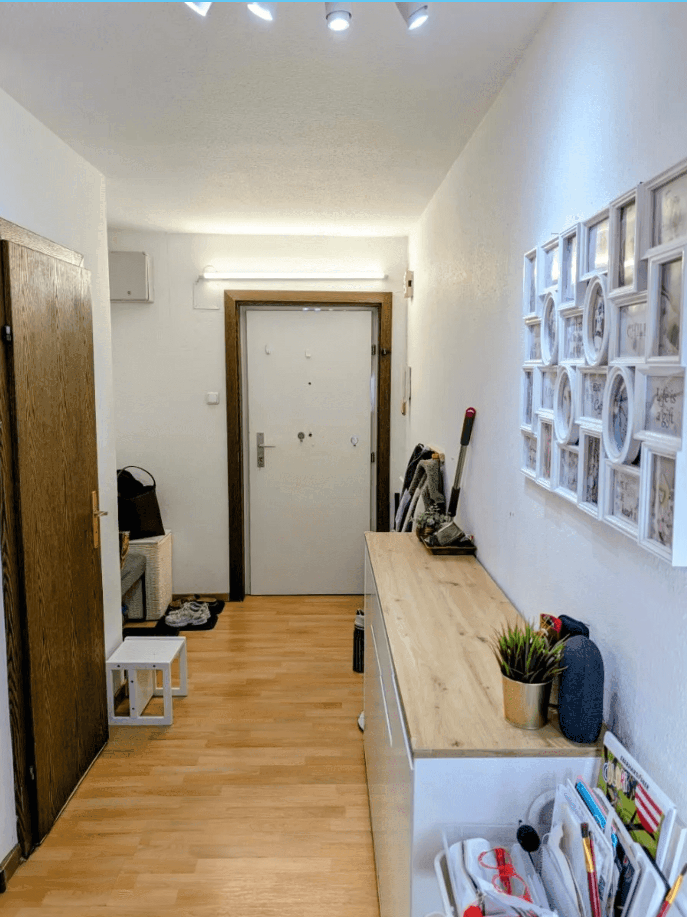 Heller Flur mit Laminatboden, weiß gestrichenen Wänden und einer modernen Bildergalerie an der Wand.