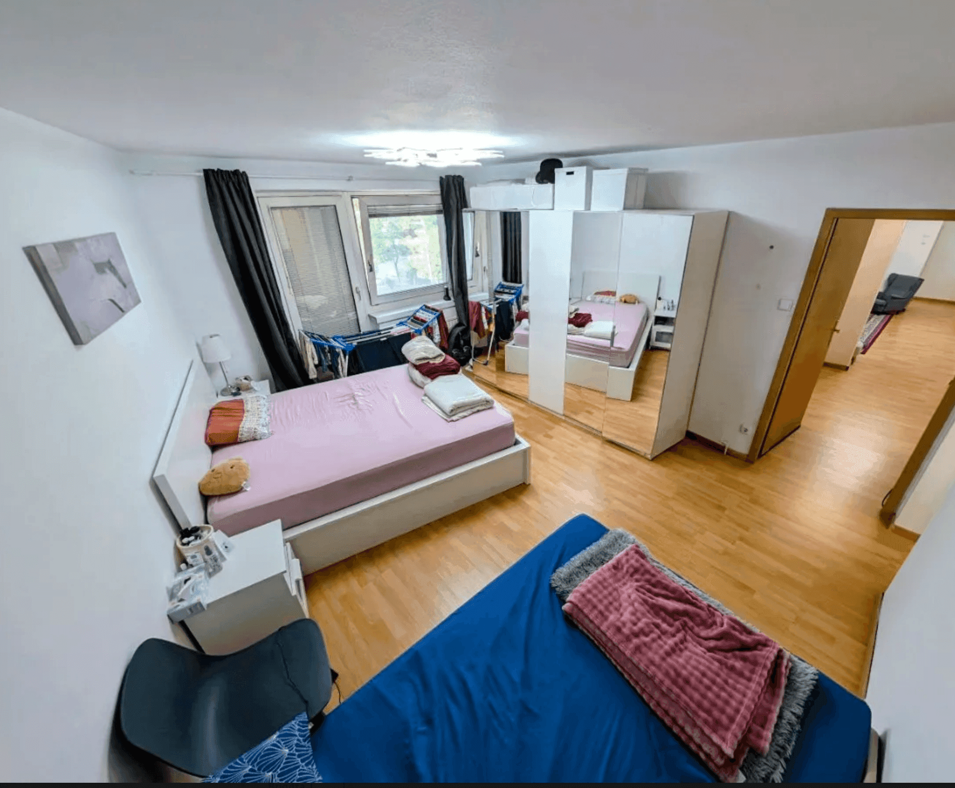 Geräumiges Schlafzimmer mit zwei Betten, Spiegelschränken und Holzboden.