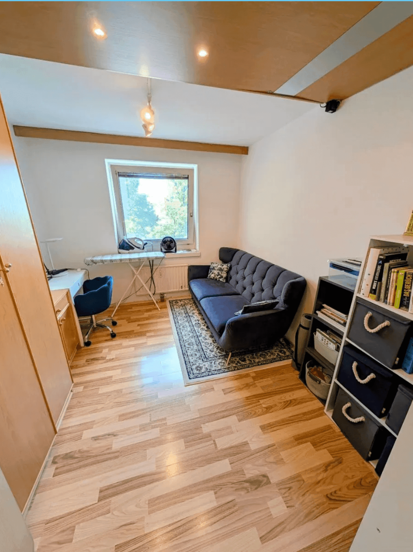 Helles Zimmer mit Schlafsofa, Schreibtisch und Fenster, bietet eine angenehme Arbeits- und Schlafumgebung.