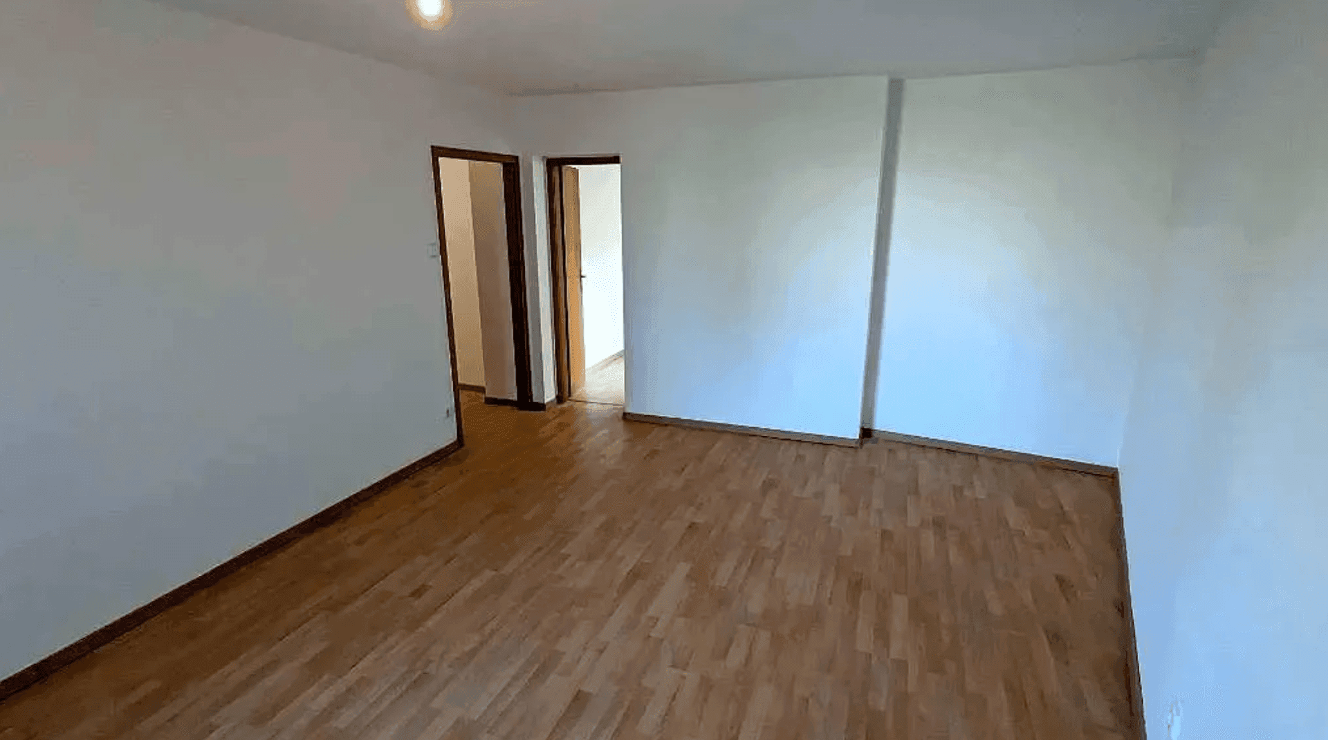 Geräumiges, unmöbliertes Zimmer mit Holzboden und Zugang zu weiteren Räumen.