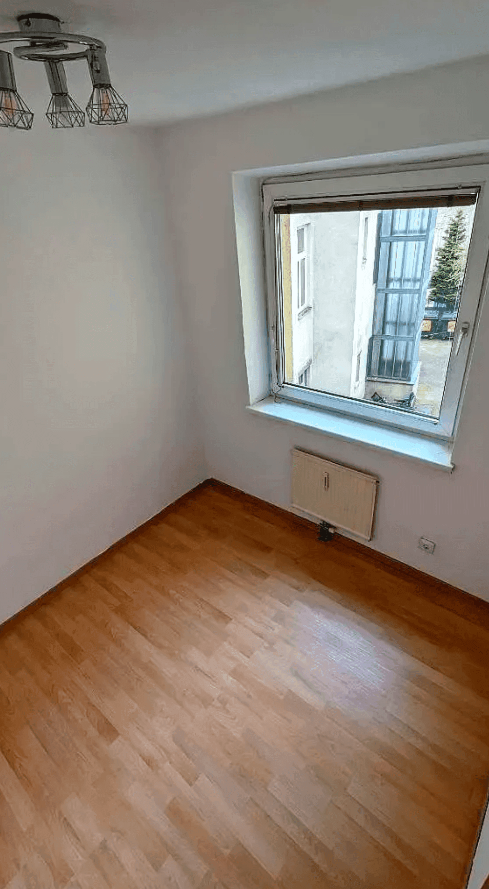 Unmöbliertes Zimmer mit Holzboden und Fenster, bietet vielseitige Nutzungsmöglichkeiten.