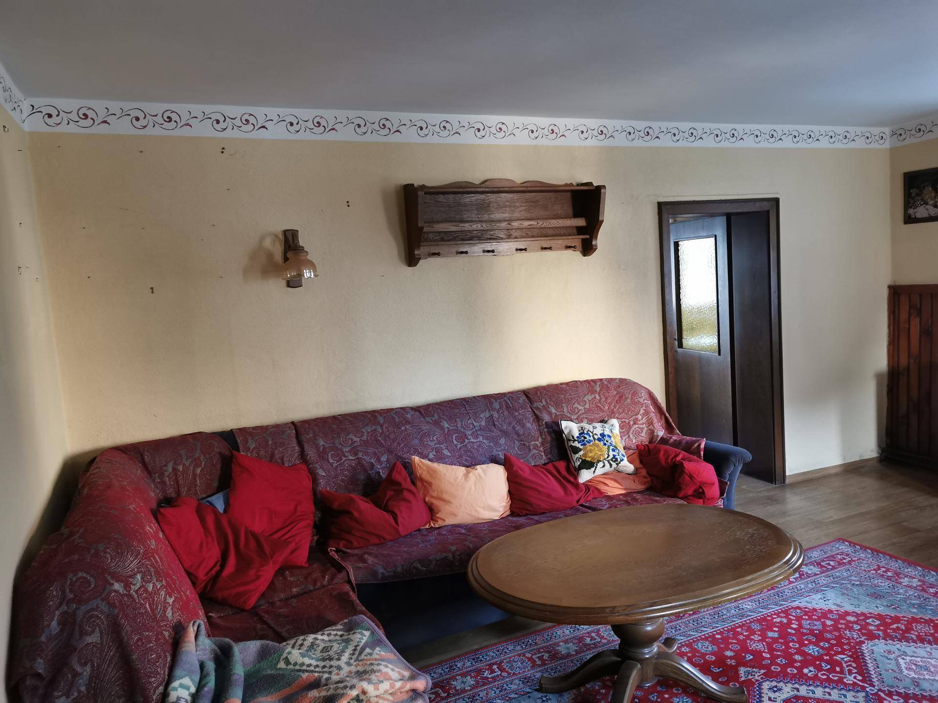 Wohnzimmer mit großem rotem Sofa, ovalem Couchtisch und dekorativer Wandbordüre.
