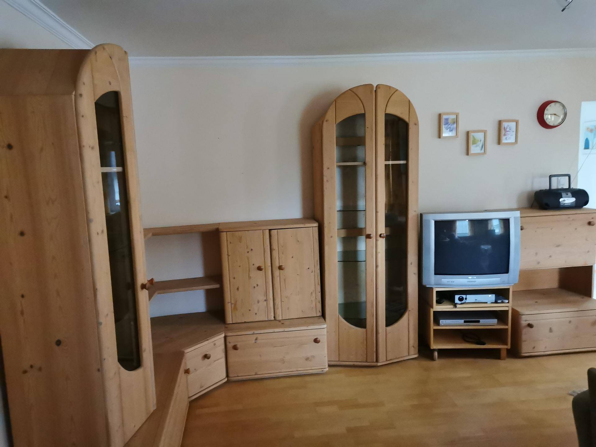 Wohnzimmer mit traditionellen Holzmöbeln, Vitrinen und einem älteren Fernsehgerät.