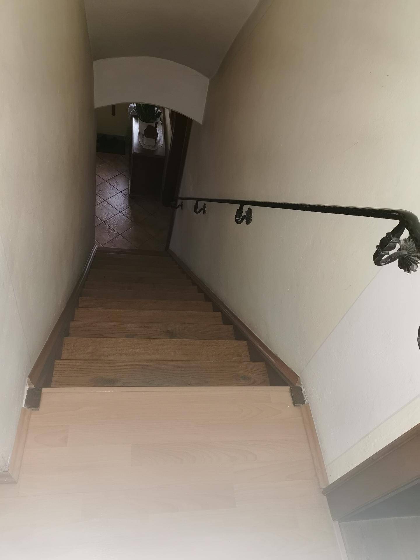 Holztreppe mit schmiedeeisernem Geländer führt in den unteren Bereich des Hauses.