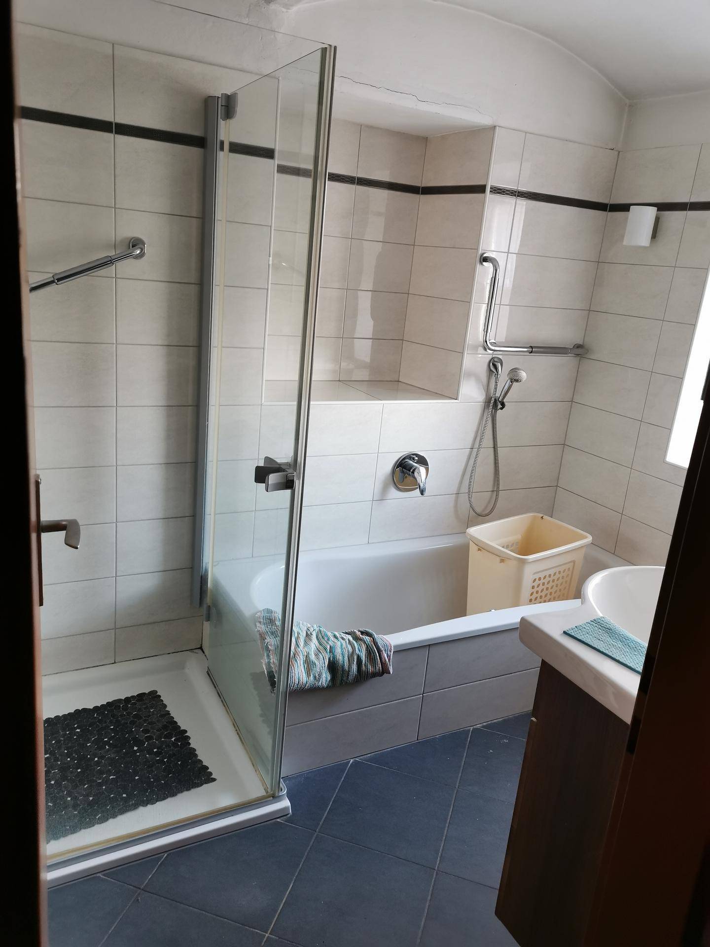 Badezimmer mit Badewanne, separater Duschkabine und Haltegriffen für mehr Sicherheit.