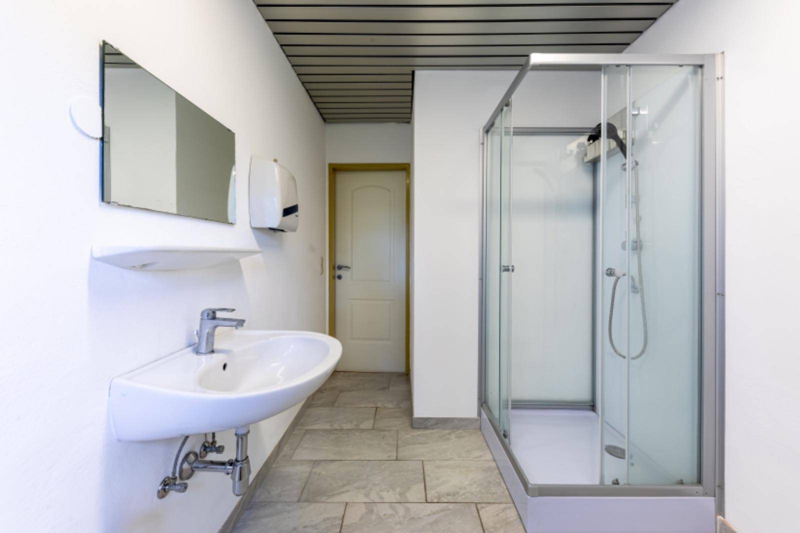 Modernes Badezimmer mit Duschkabine, Waschbecken und hellen Fliesen.