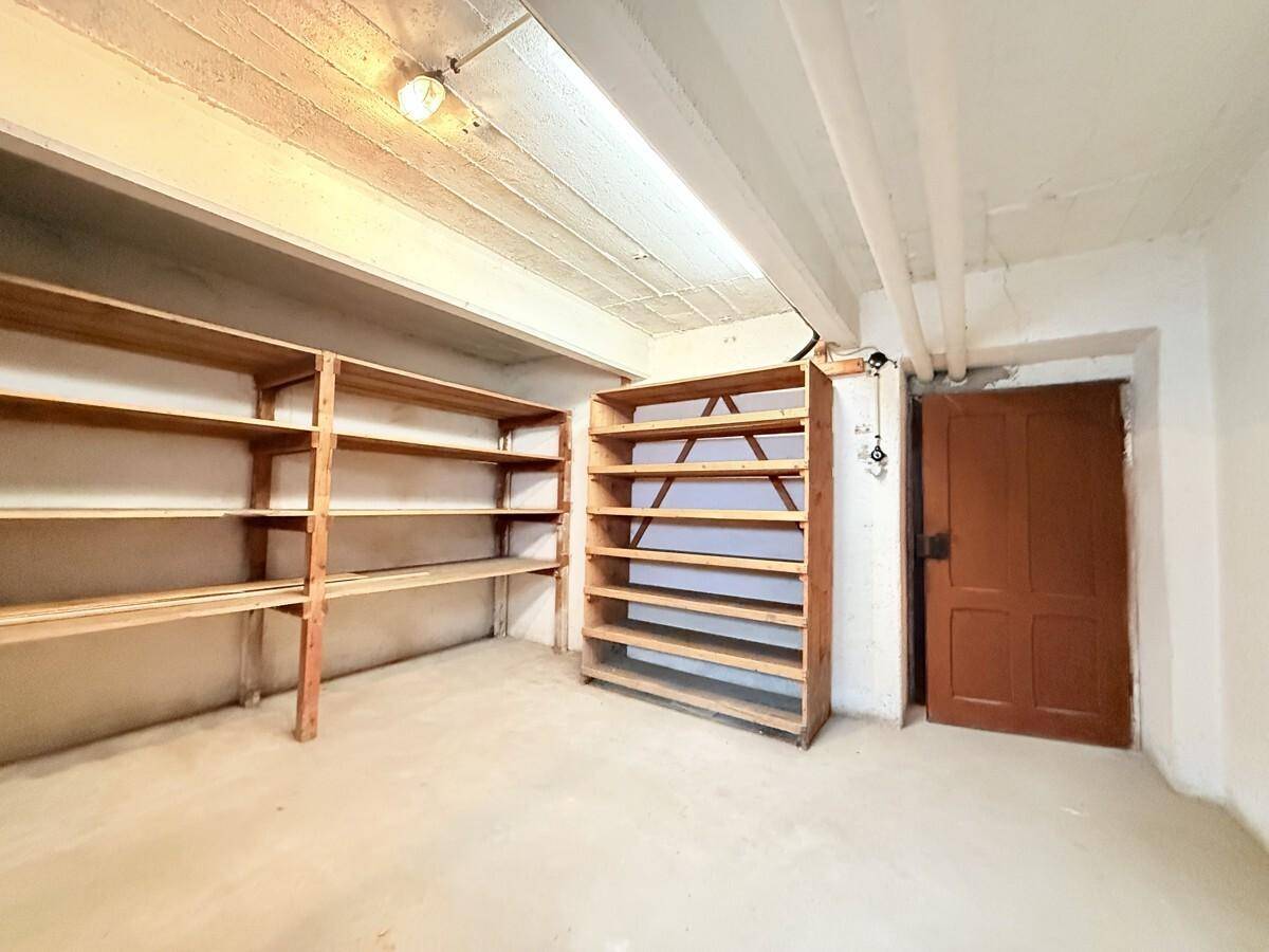 Praktischer Abstellraum mit stabilen Holzregalen für zusätzlichen Stauraum und einer Holztür.