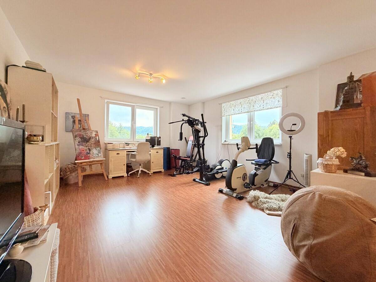 Vielseitiger Raum mit Fitnessgeräten, Schreibtisch und Fenstern mit Weitblick.