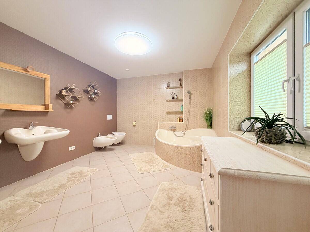 Geräumiges Badezimmer mit Eckbadewanne, Doppelwaschbecken und hellen Fliesen.