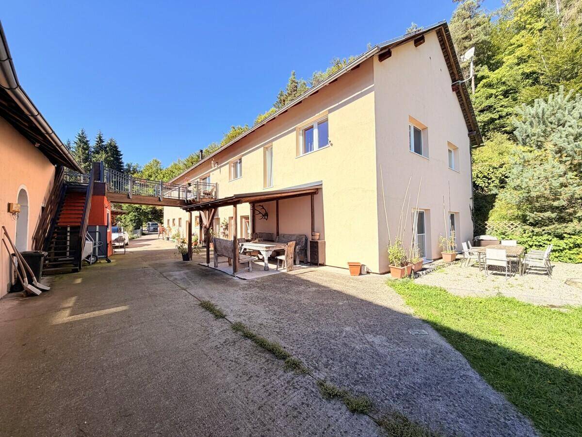 Große Terrasse mit überdachtem Sitzbereich und weiteren Gartenmöbeln neben dem Haus.