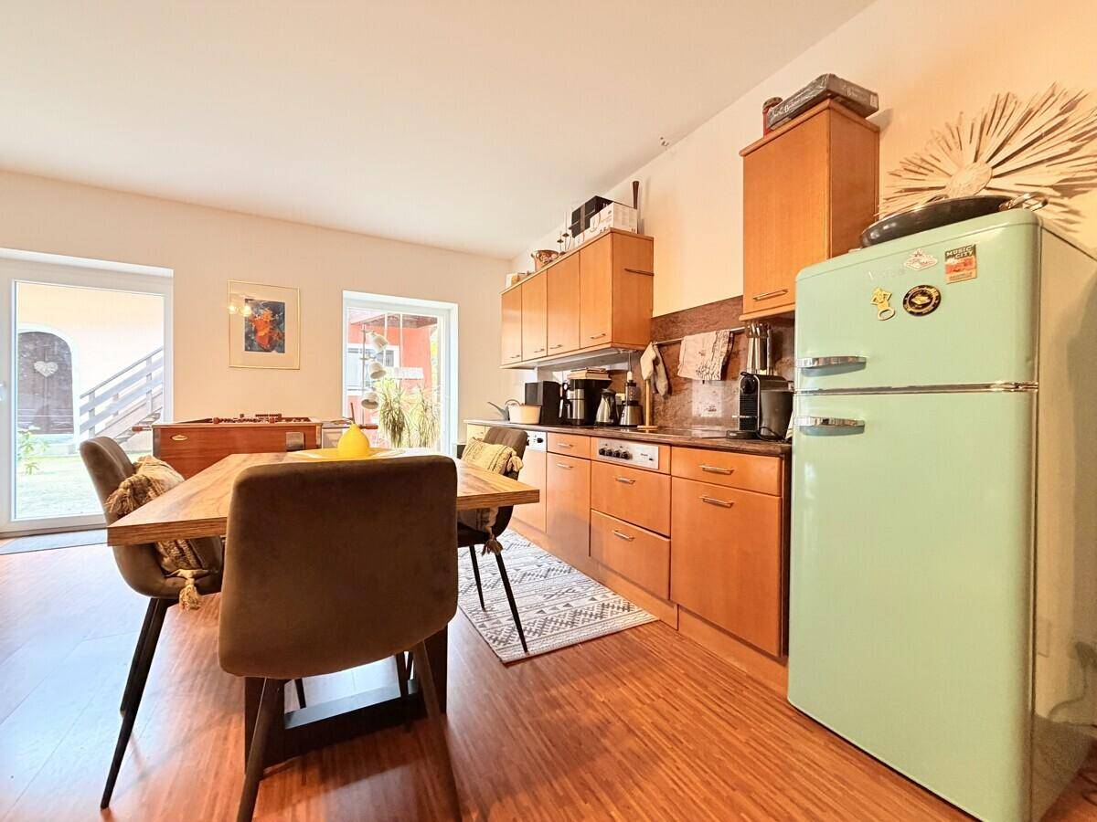 Funktionale Küche mit Holzelementen, Esstisch und einem Retro-Kühlschrank.